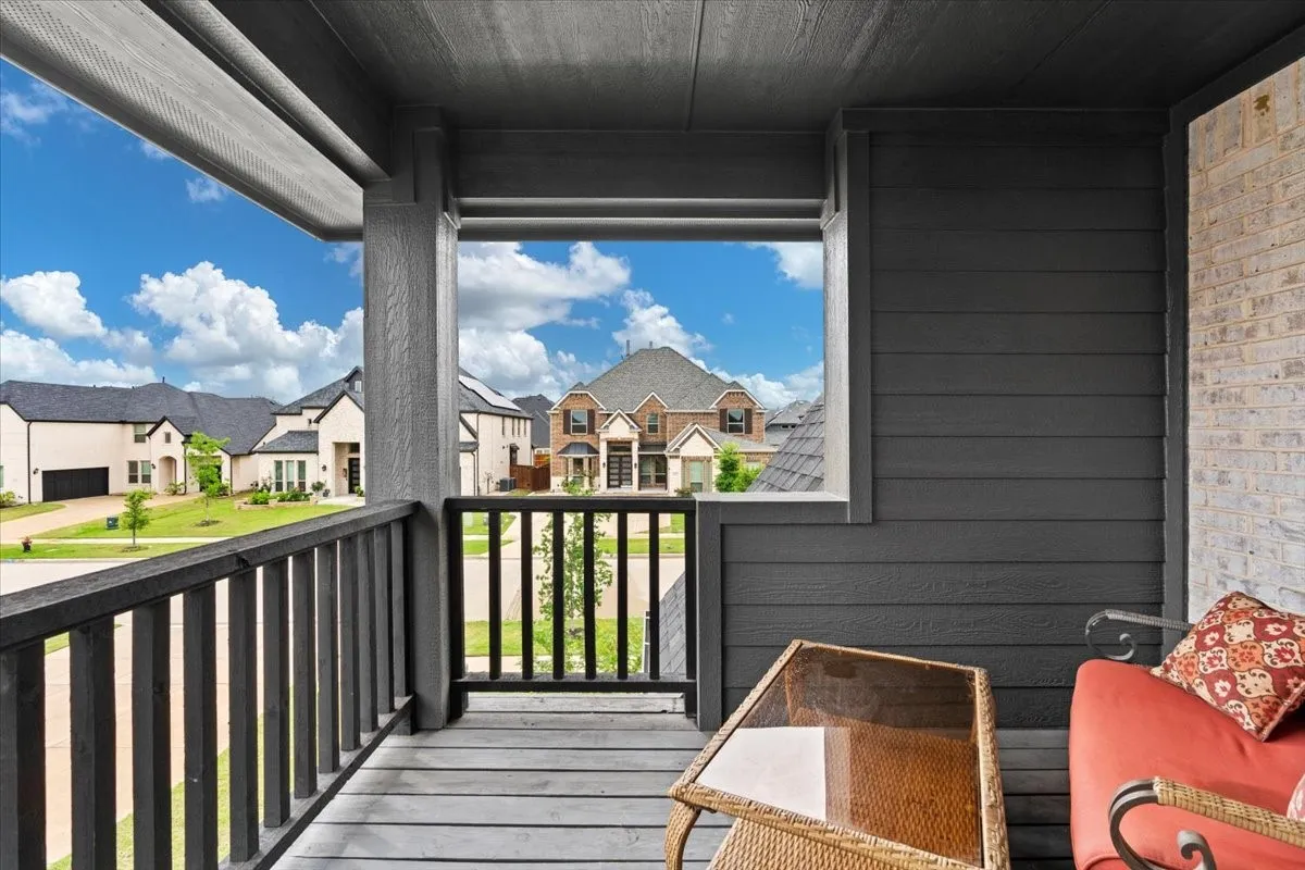 Covered porch featuring dark wood-finish decking and railing, dark horizontal siding, and a light-colored brick wall