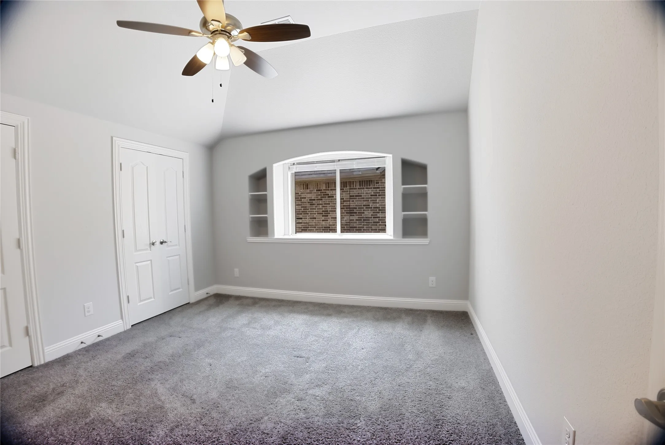 Room featuring neutral-toned walls, gray carpeting, and a ceiling fan with integrated lighting