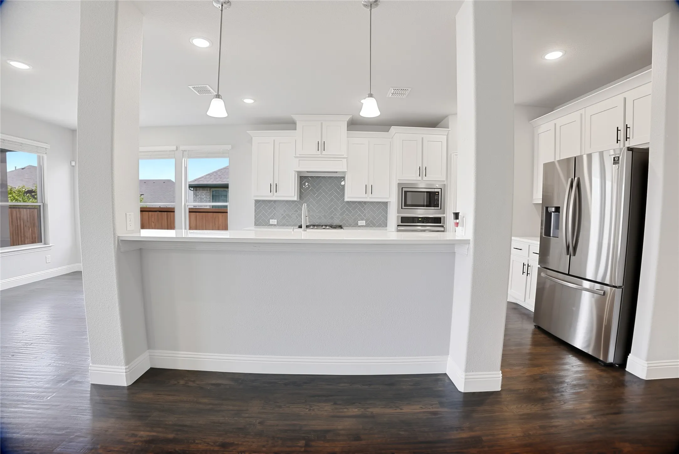 Modern kitchen featuring white shaker cabinetry, stainless steel appliances, a breakfast bar, recessed lighting, and wood-finish flooring