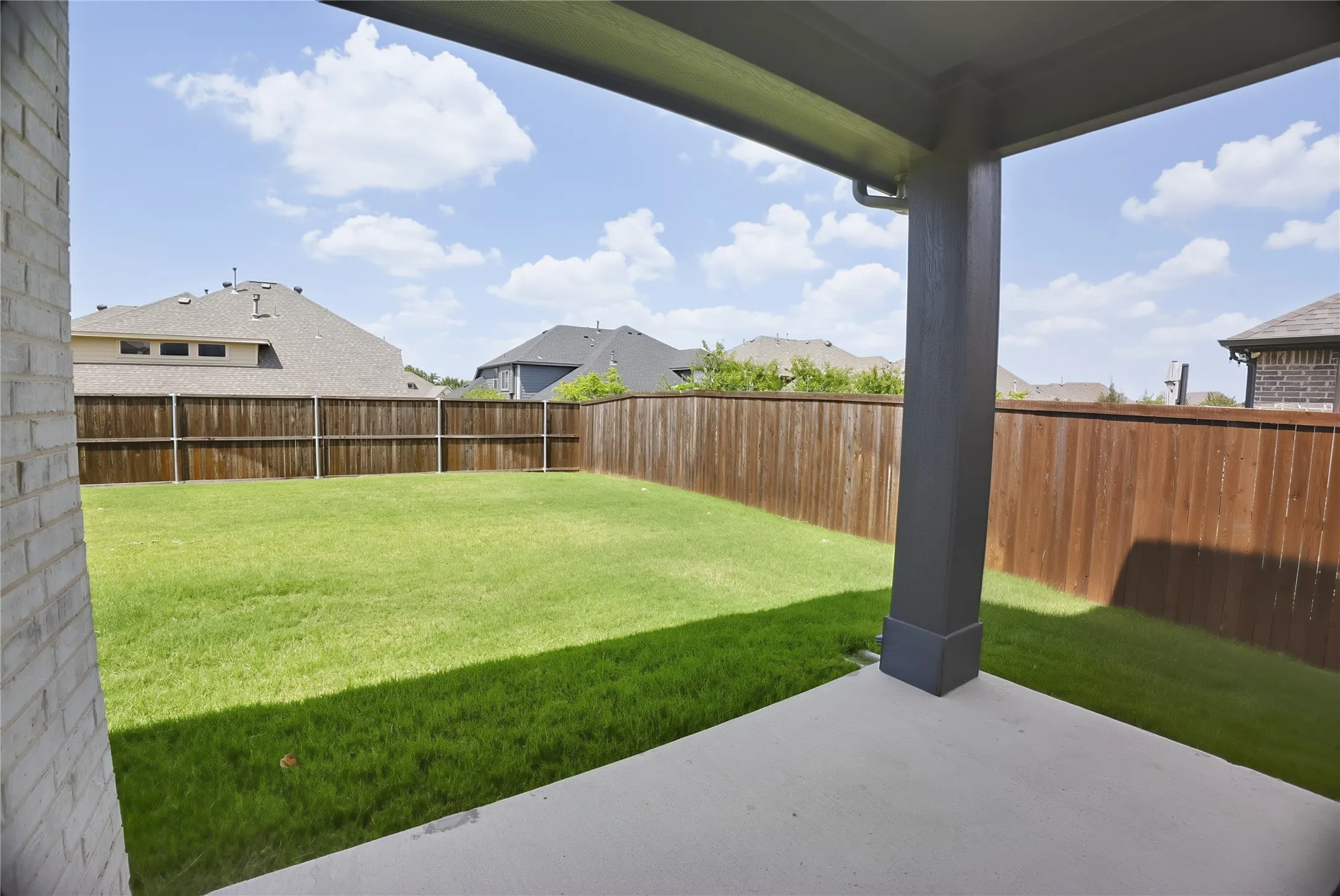 Covered patio with a concrete surface, featuring a square column support and a rain gutter system