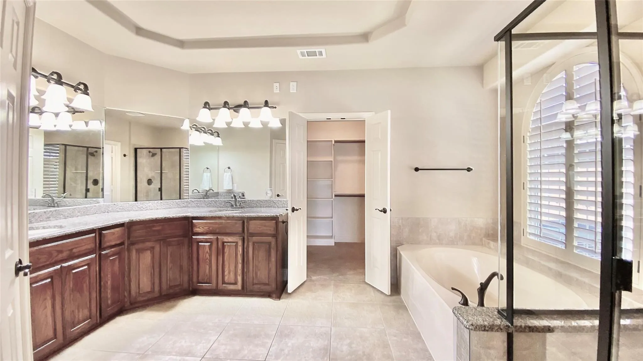 Spacious bathroom featuring dual vanities with expansive countertops, a separate soaking tub, and a shower enclosure