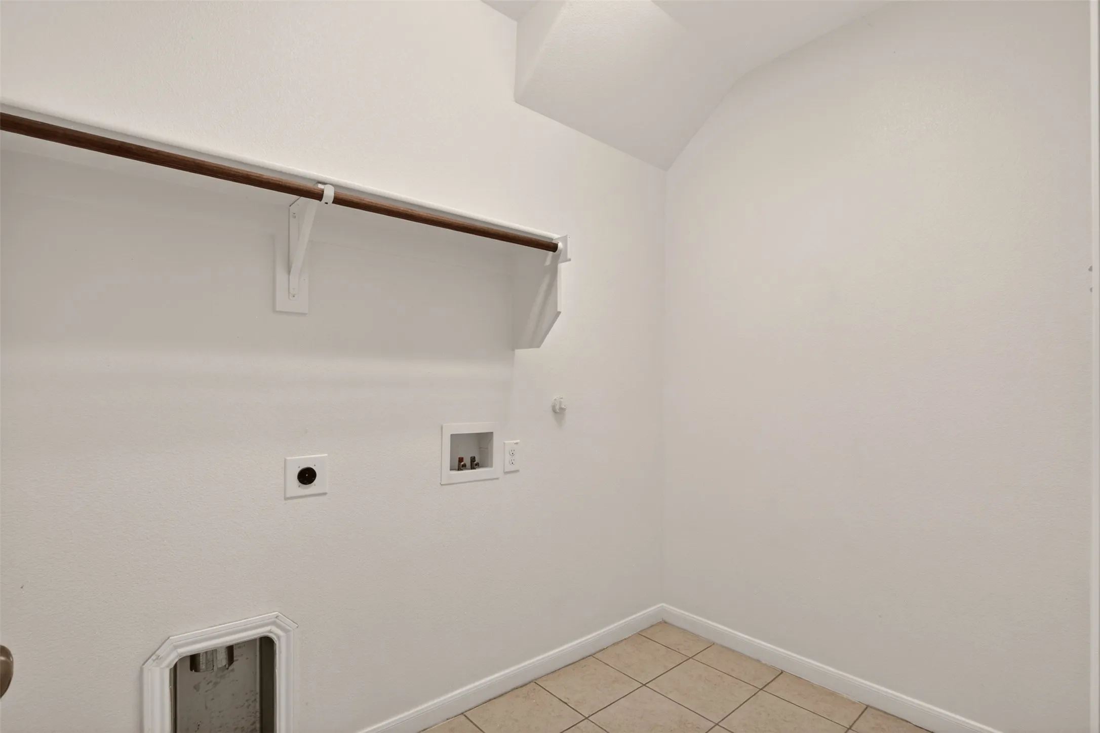 Dedicated utility space featuring tile flooring, white walls, and a built-in hanging rod