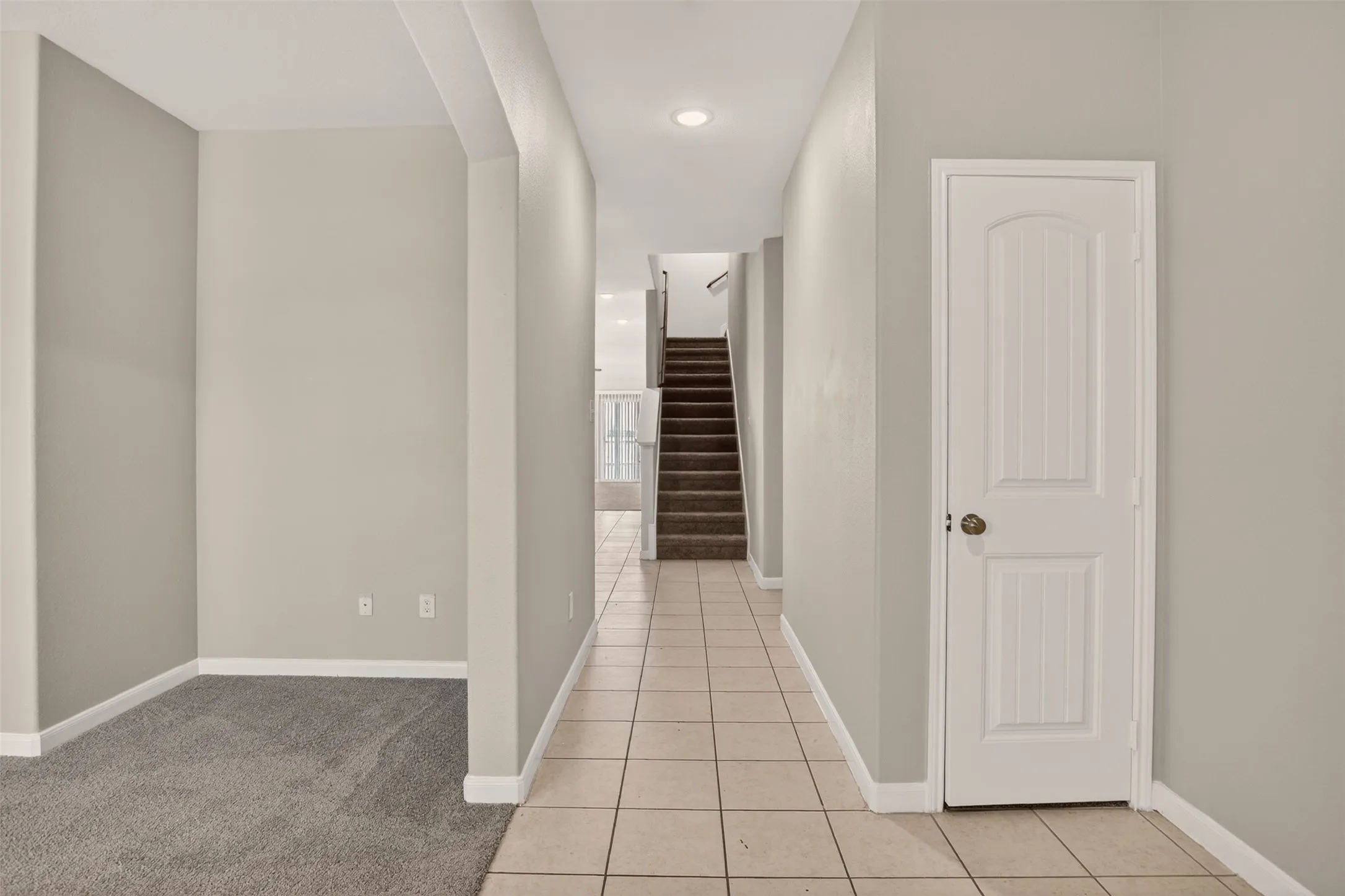 Tiled entry hallway featuring recessed lighting and a carpeted staircase