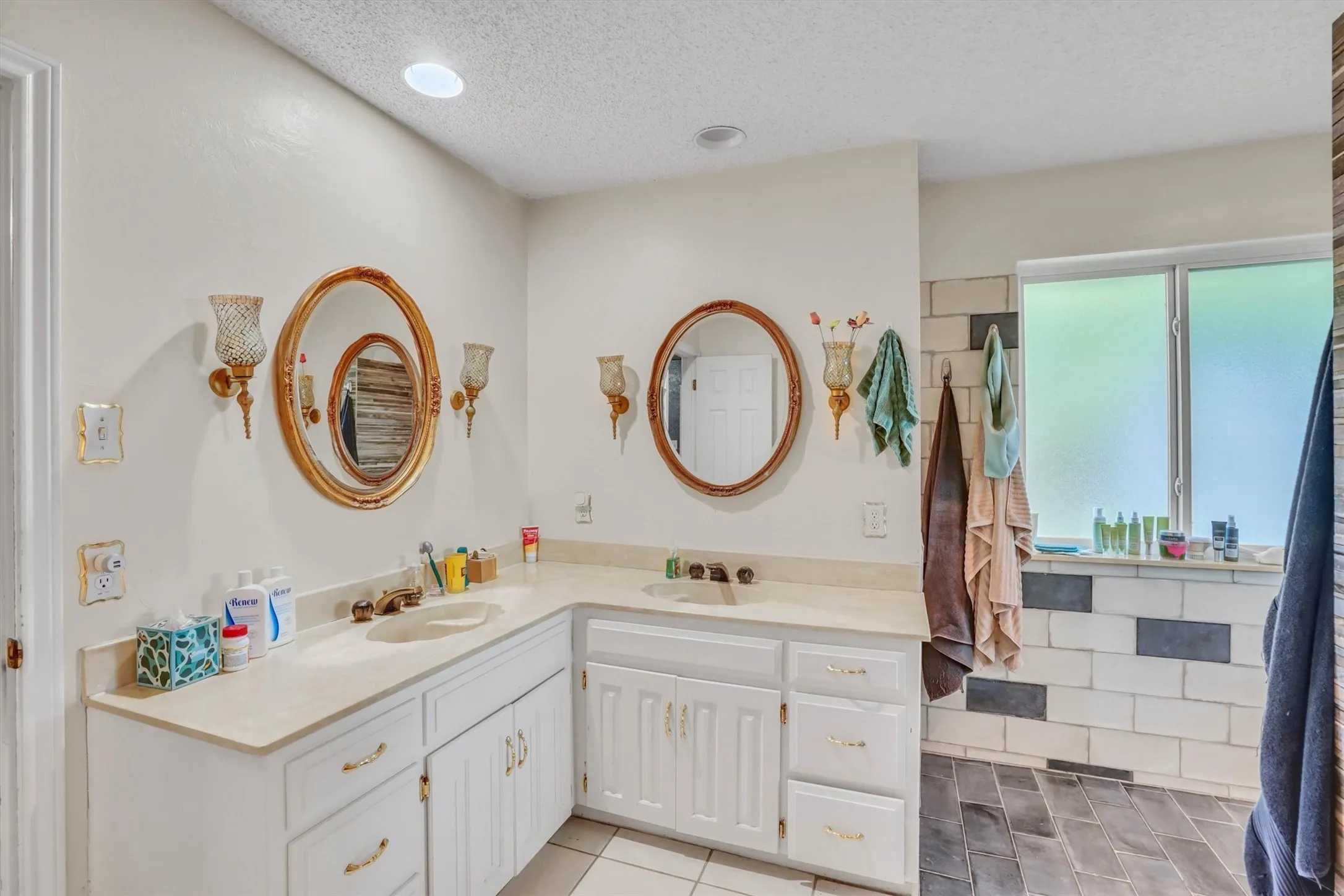 Bathroom featuring a dual vanity with light-toned countertops and white cabinetry