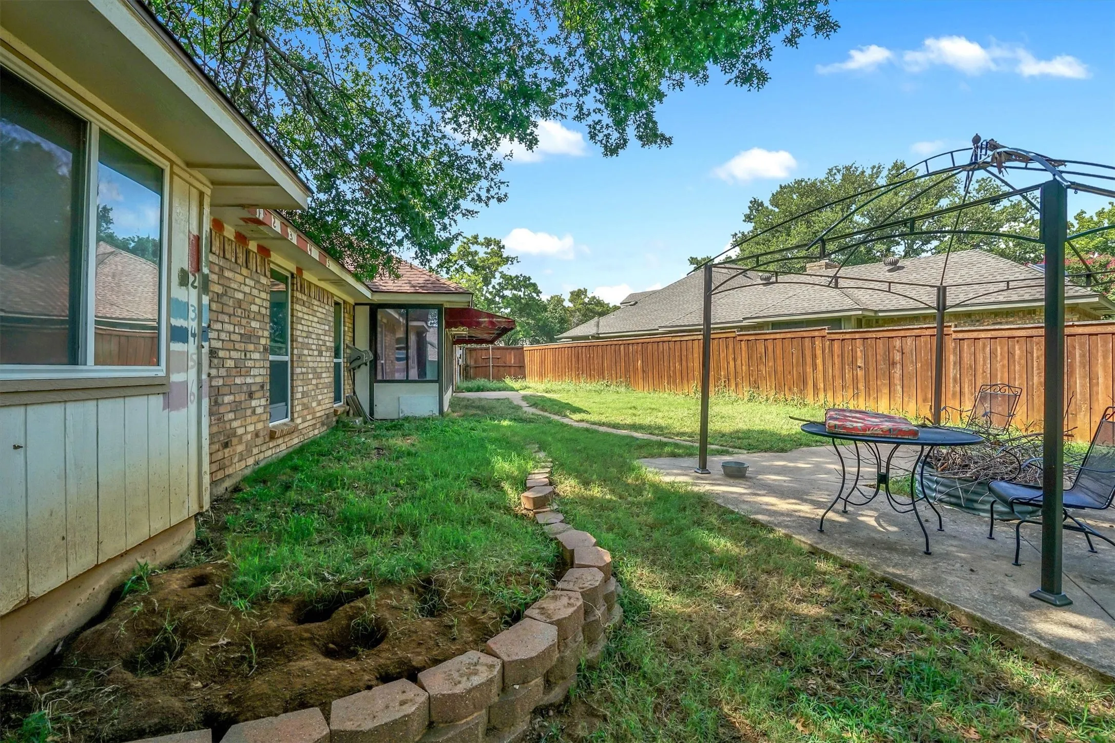 Expansive backyard featuring a partial brick exterior, a concrete patio area, and a privacy fence