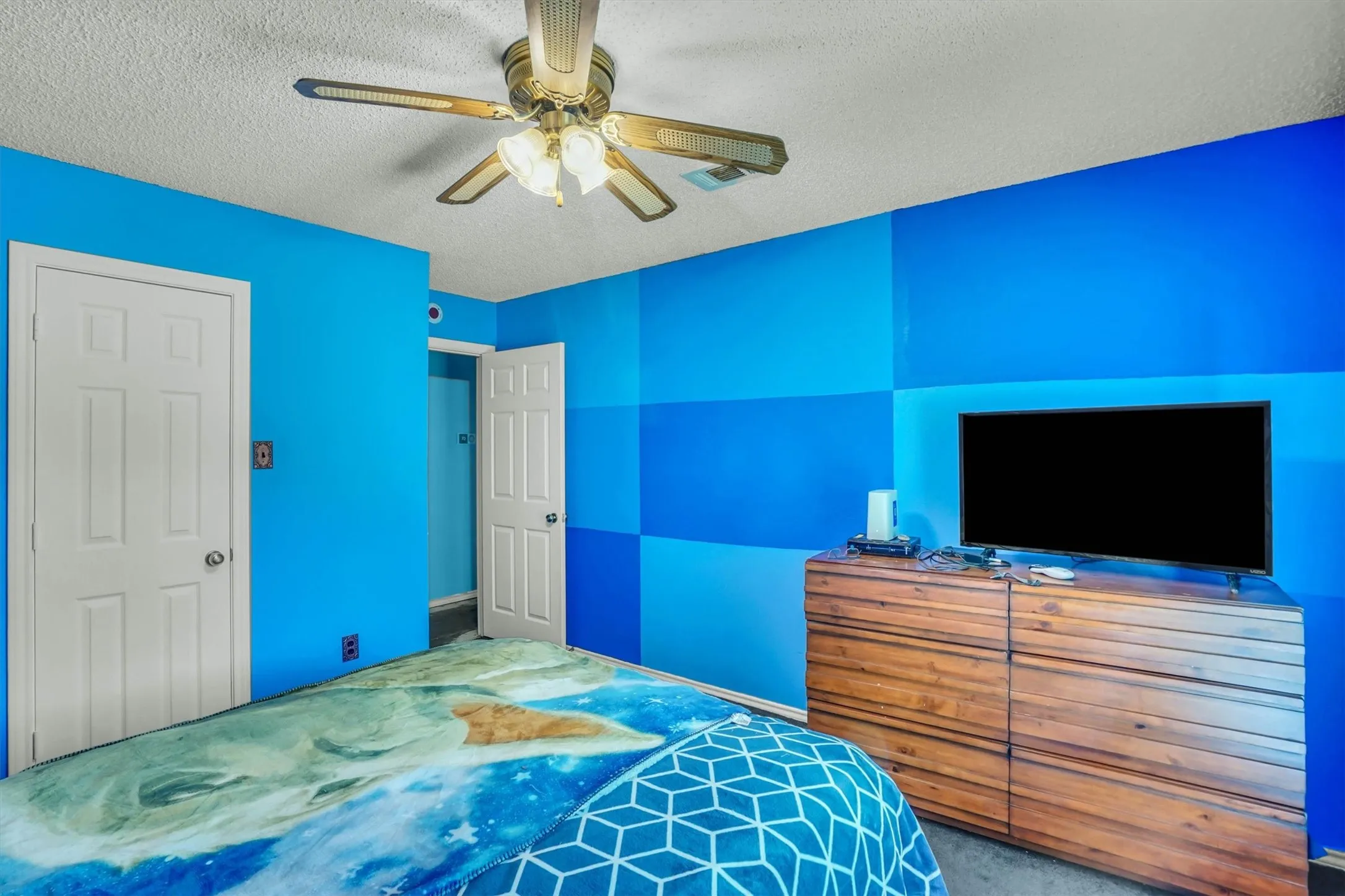 Room featuring a ceiling fan with integrated lighting, two paneled doors, and a wood-finish dresser