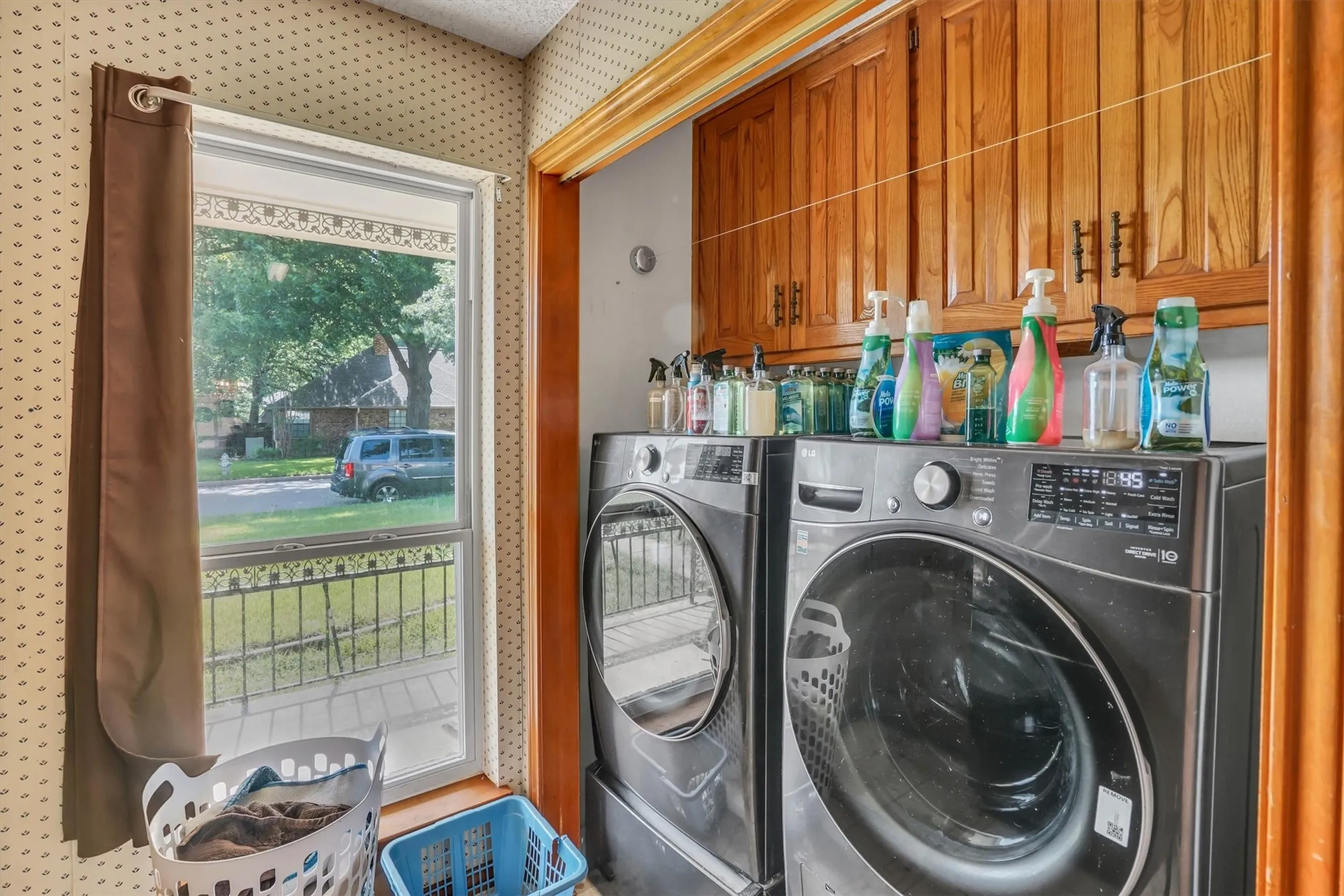 Utility area featuring wood cabinetry, a large window, and patterned wallpaper