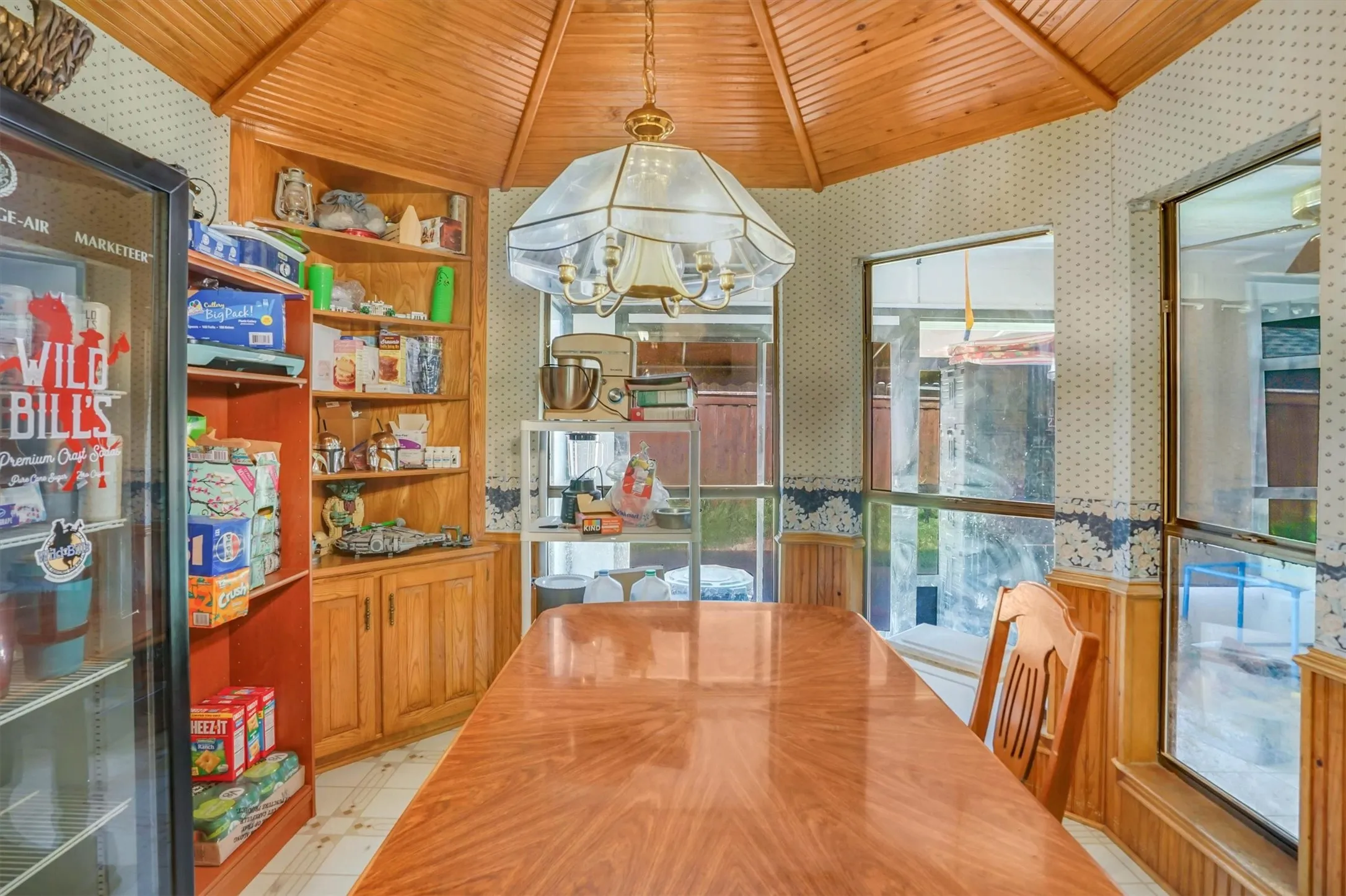 Dining area featuring a wood-panel accent ceiling, corner built-in shelving with cabinet storage, and multiple windows