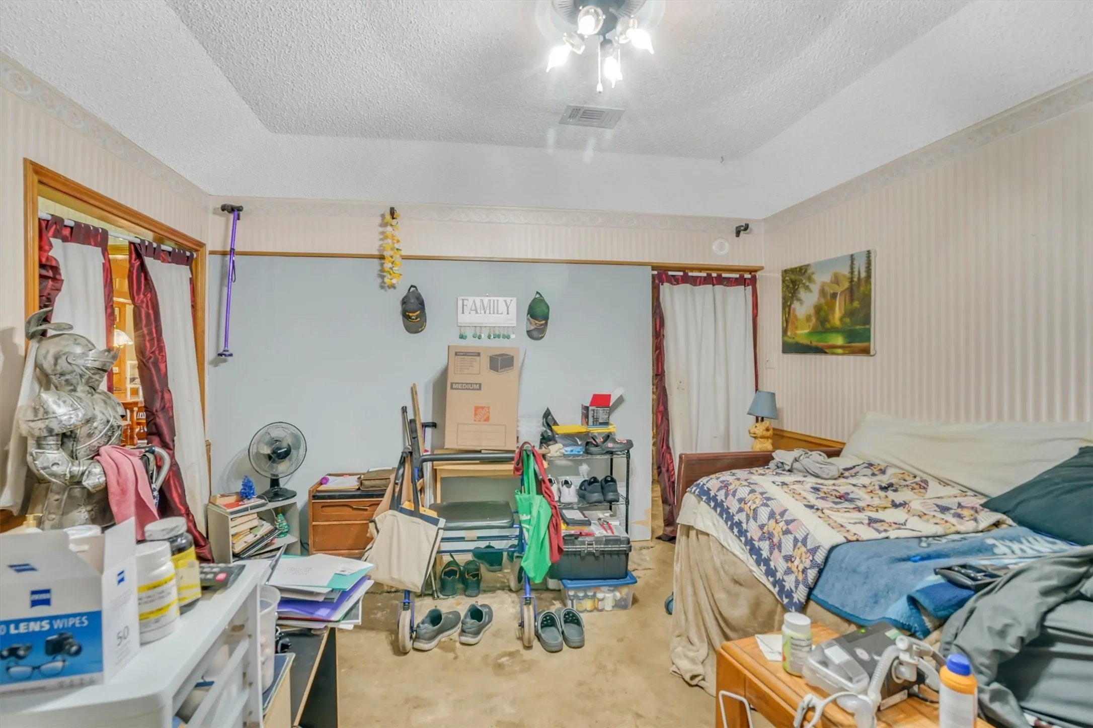 Carpeted room featuring a tray ceiling with a ceiling fan, a wood-framed doorway, and a picture window with curtains