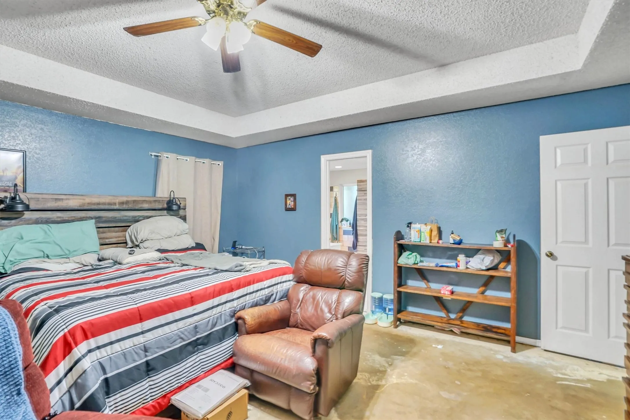 Spacious room featuring a tray ceiling, ceiling fan, and blue painted walls