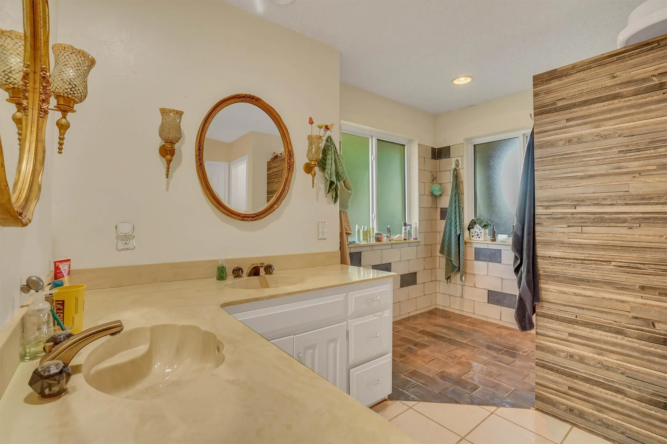 Bathroom vanity featuring a shell-shaped basin, a brass-toned faucet, and a stone-finish countertop