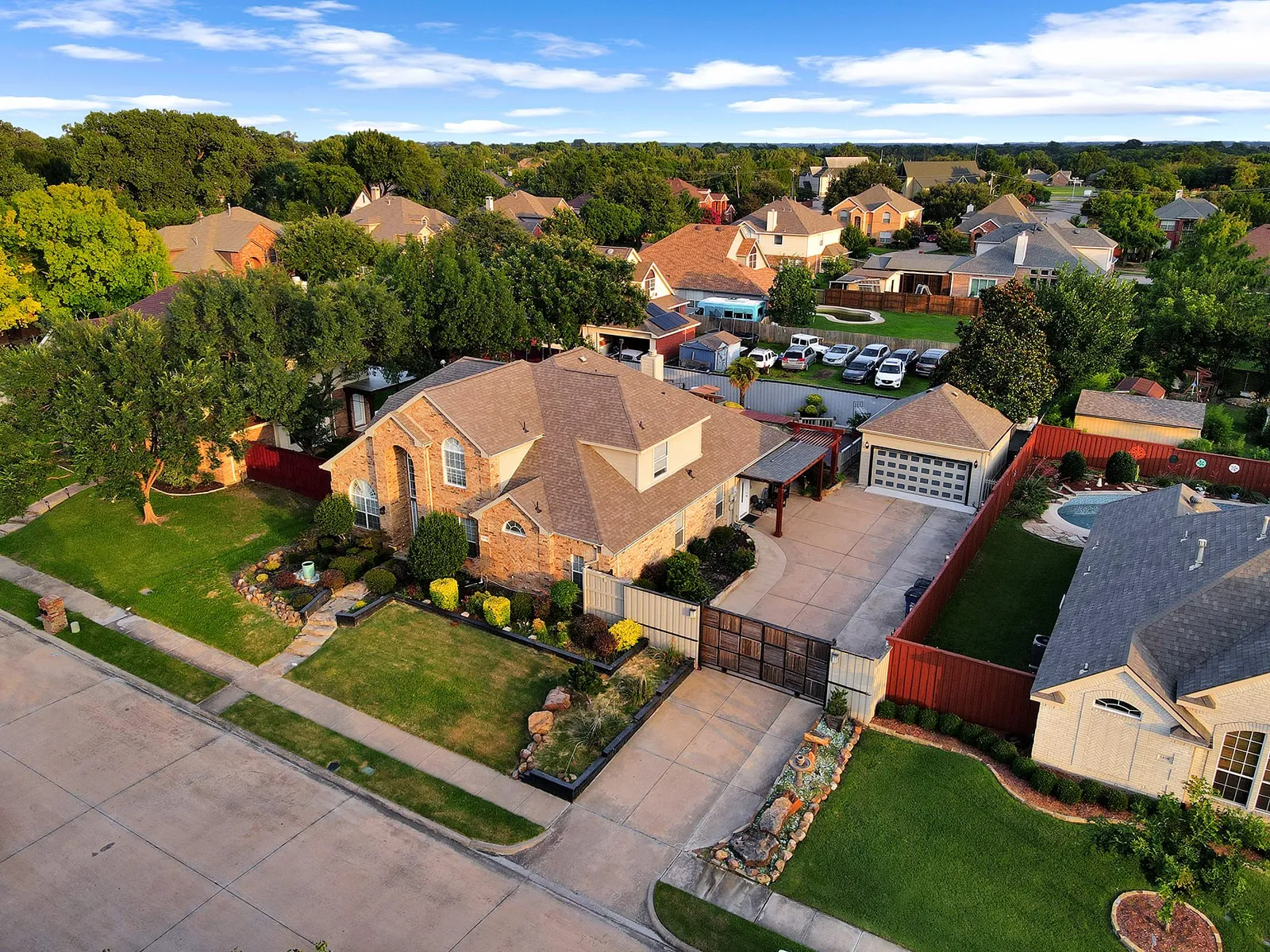 Brick exterior with a detached garage, private drive with gate, front landscaping, and a backyard pool