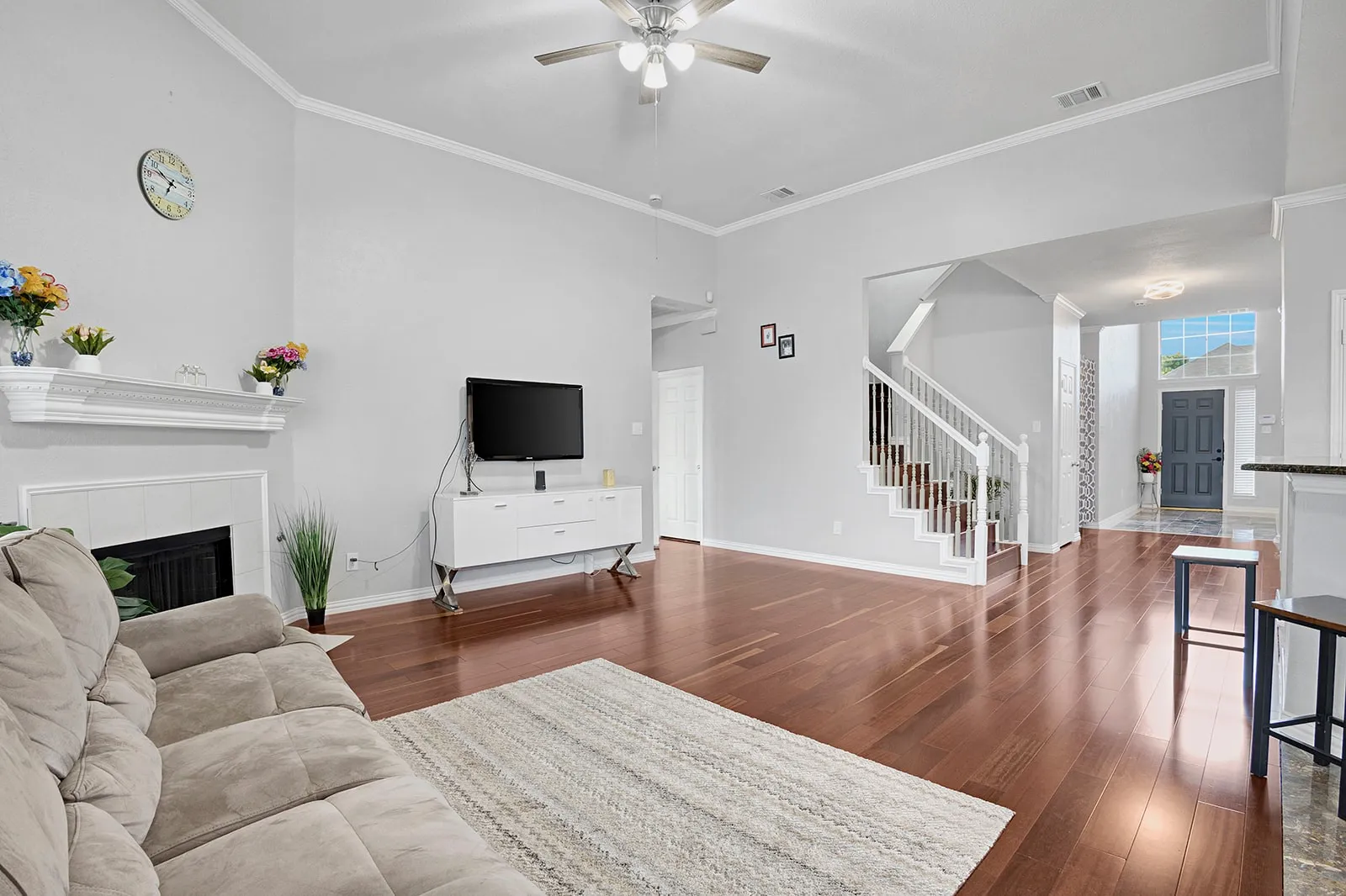 Living area featuring dark wood-finish flooring, a white tile fireplace with mantle, and a vaulted ceiling