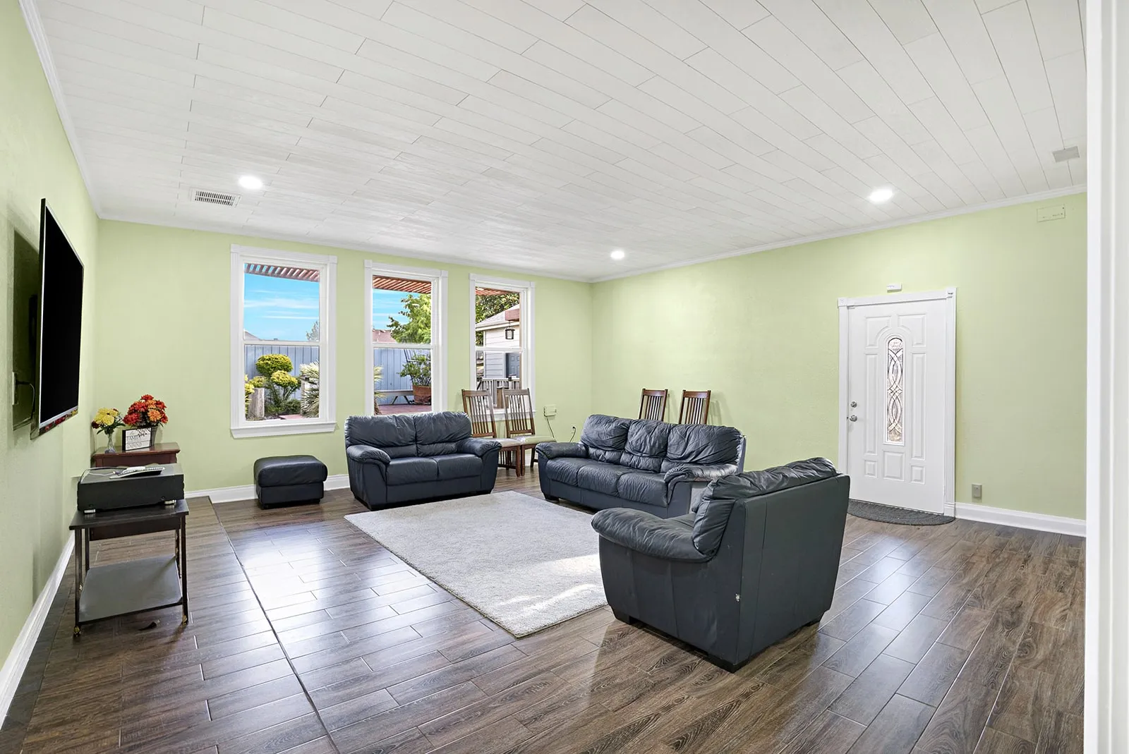 Living space featuring wood-finish flooring, light green walls, a white shiplap ceiling with recessed lighting, and multiple windows