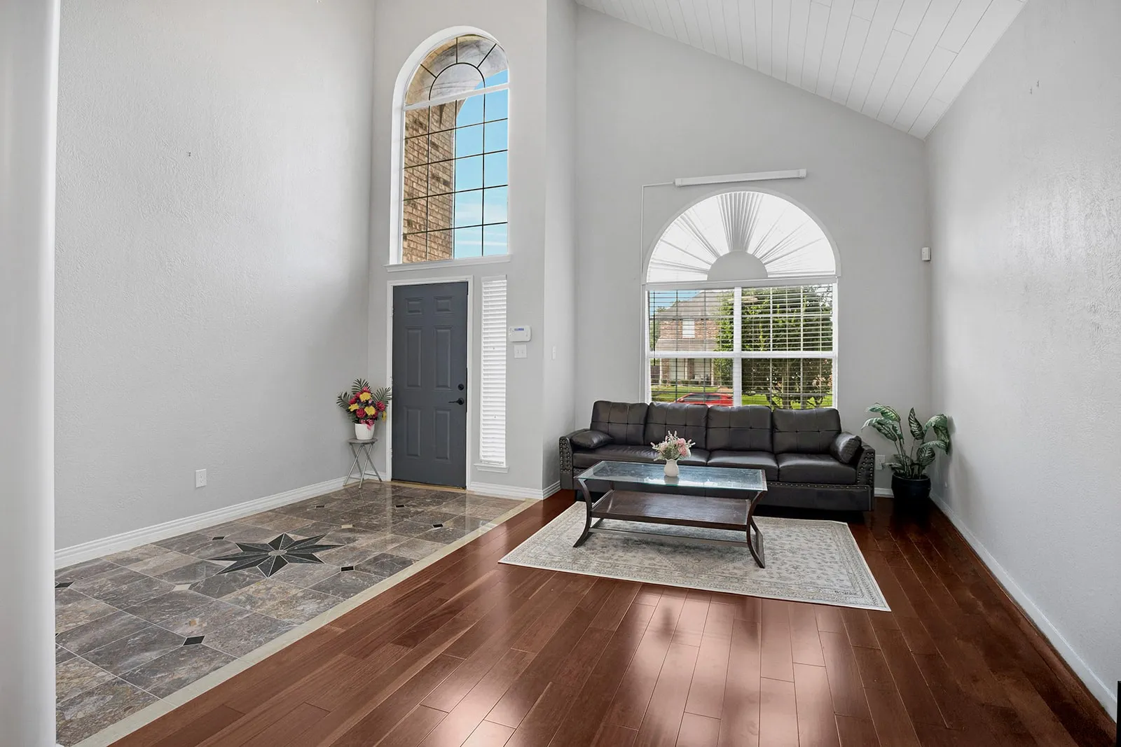 Living area featuring rich wood-finish flooring, a fireplace with a white mantel, and a ceiling fan