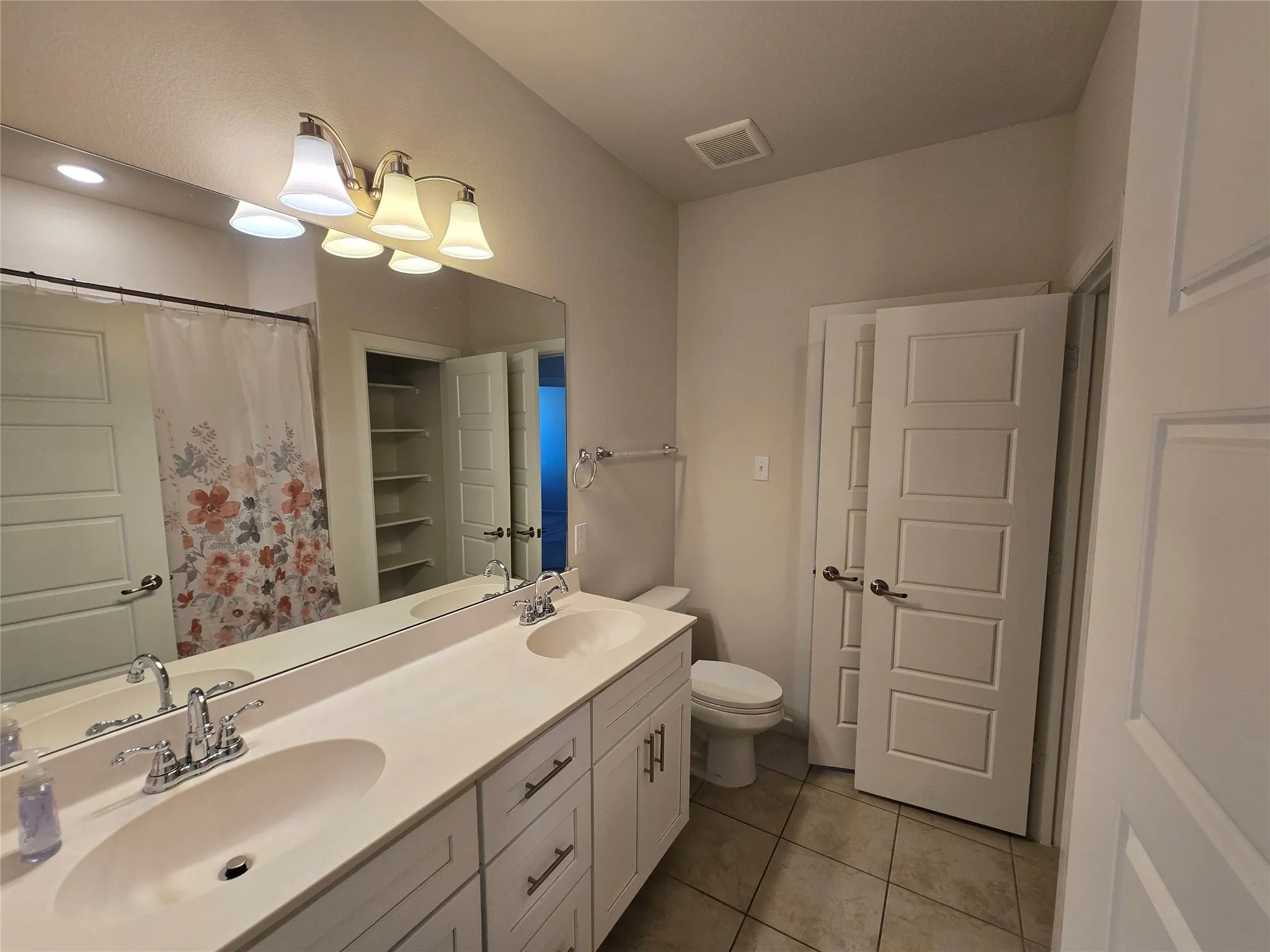 Double vanity with integrated sinks, chrome fixtures, and white cabinetry