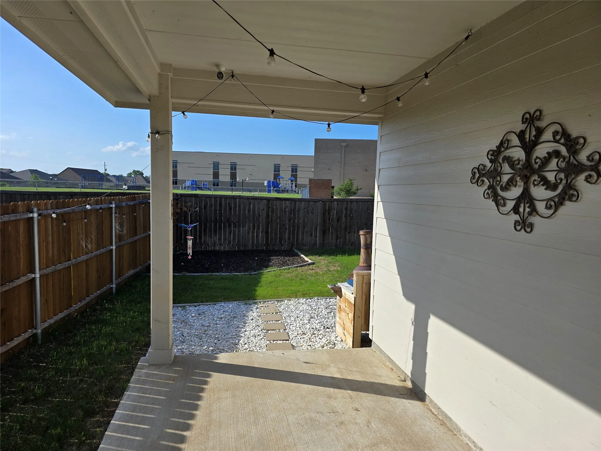 Concrete patio featuring a covered structure, wood fencing, and a gravel pathway