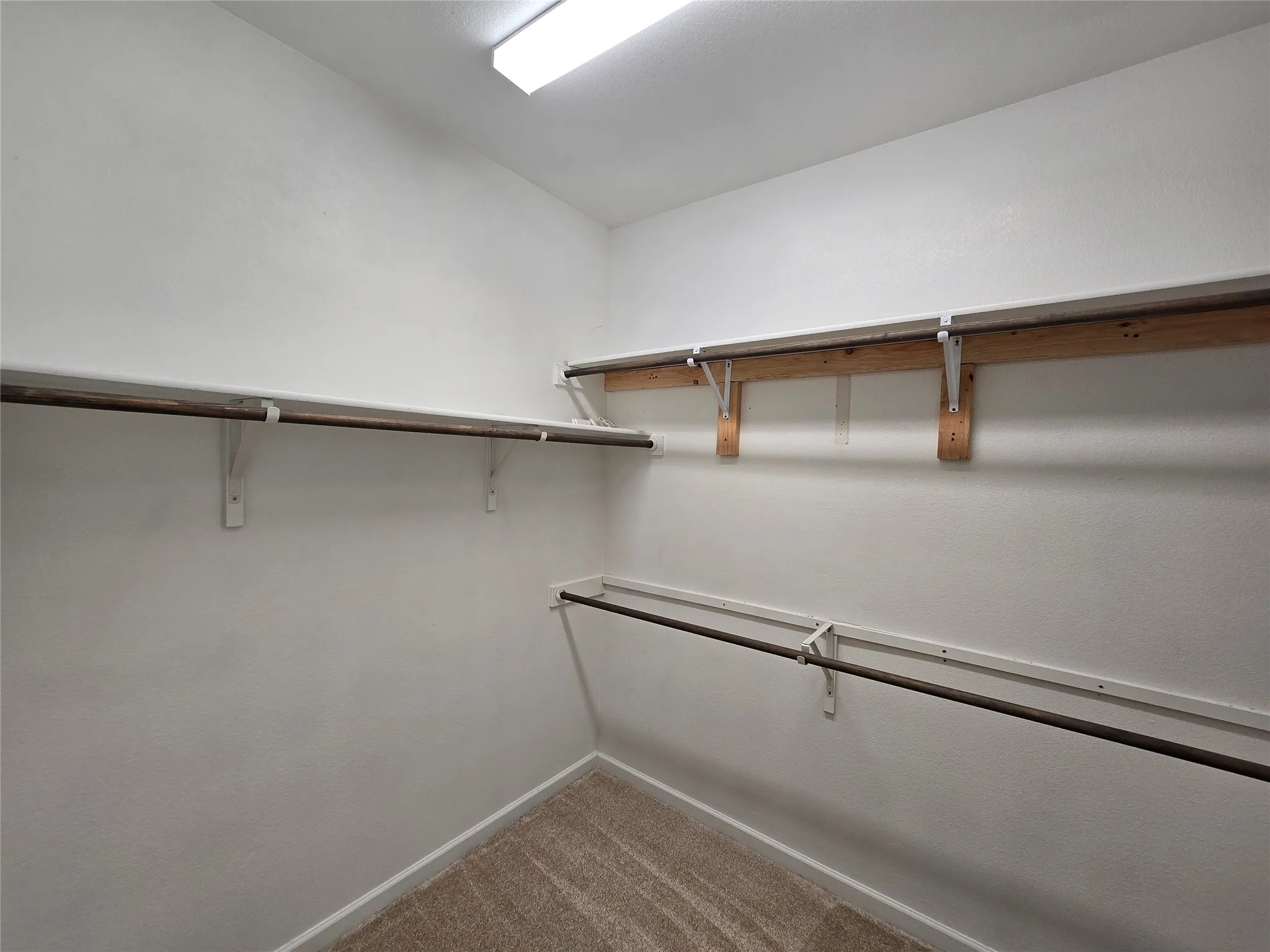 Walk-in closet with multiple levels of shelving and hanging rods