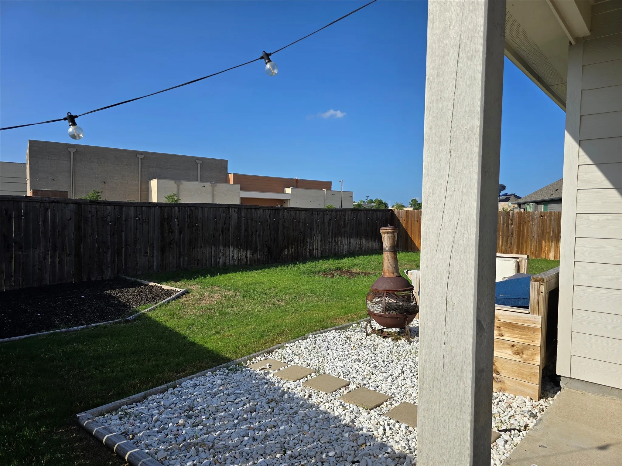 Private backyard featuring a wooden privacy fence, manicured lawn, and a decorative white gravel patio area with stepping stones