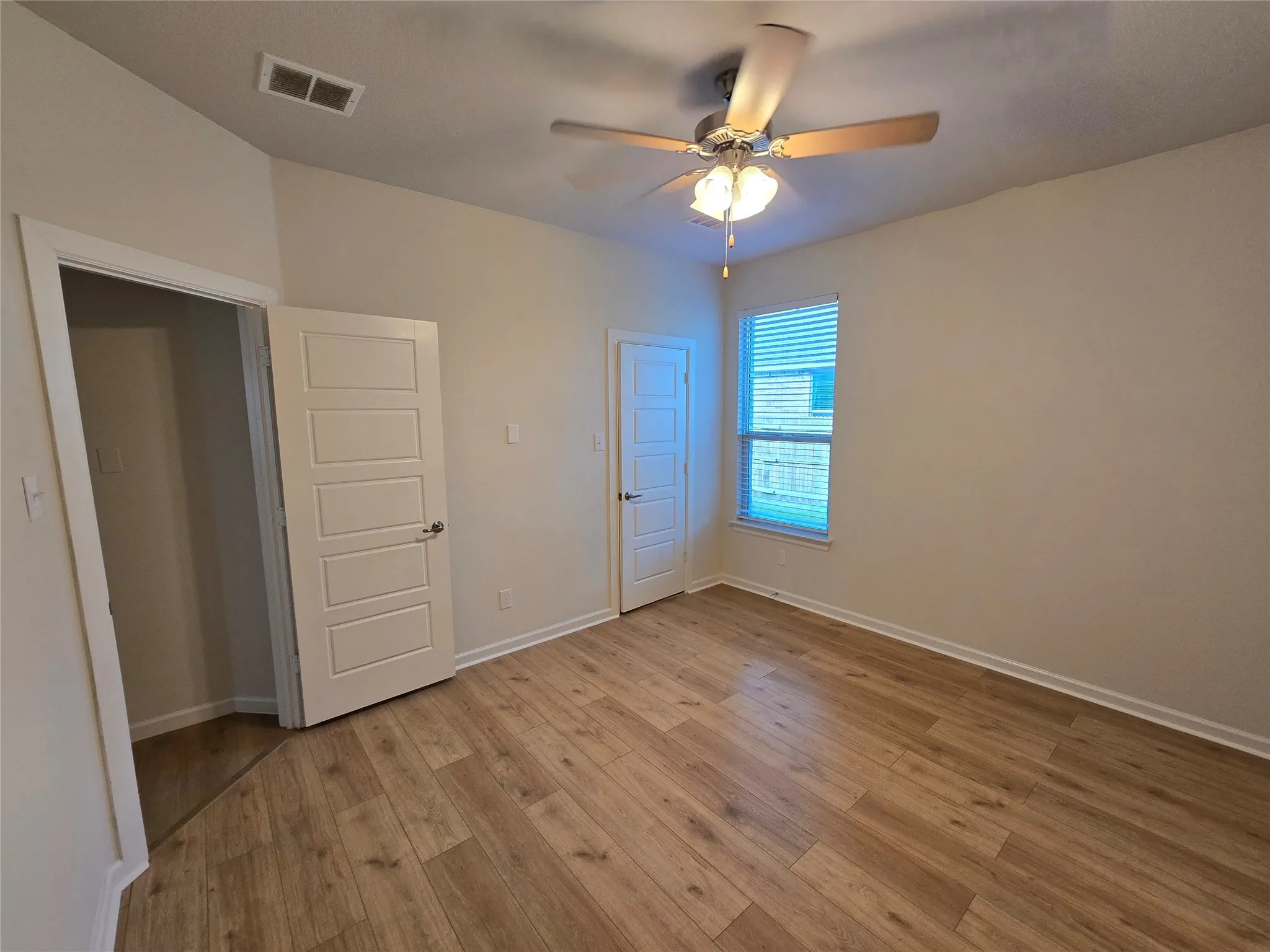 Bright room featuring wood-finish flooring and a ceiling fan with integrated lighting