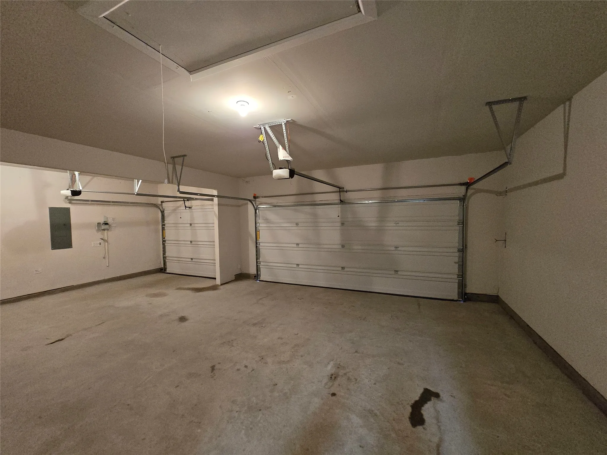 Spacious two-car garage featuring a concrete floor, two individual garage doors, and integrated garage door openers