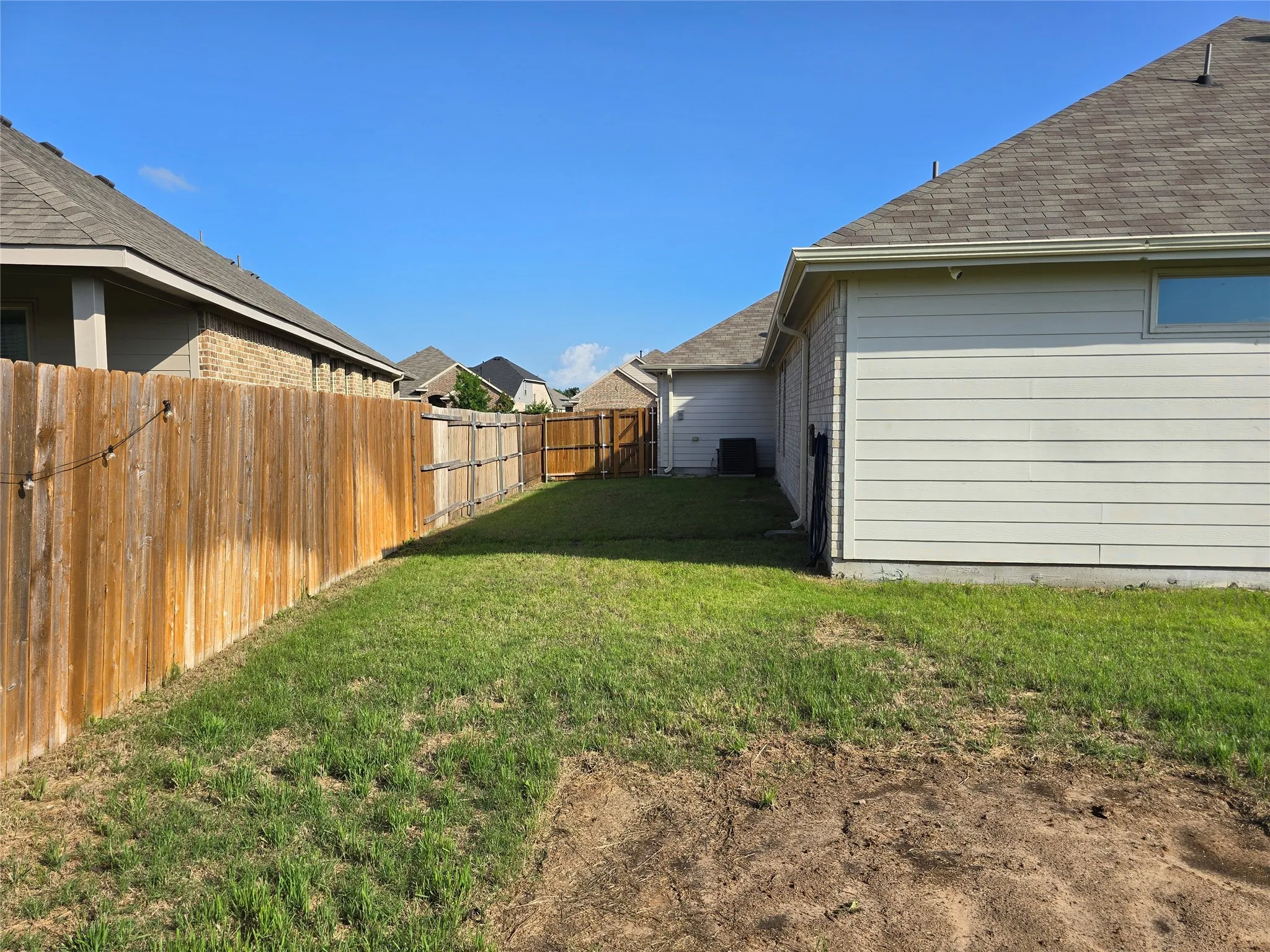 Expansive backyard featuring a wood fence, partial sod, and established perimeter structures