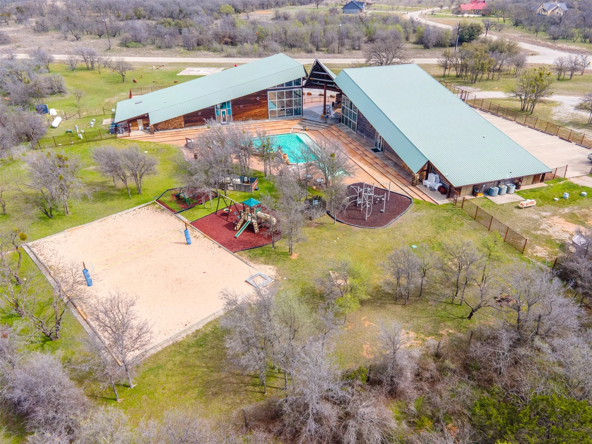 Expansive outdoor recreational area featuring a large sand court, a dedicated play structure with swings and slides, and a separate climbing structure