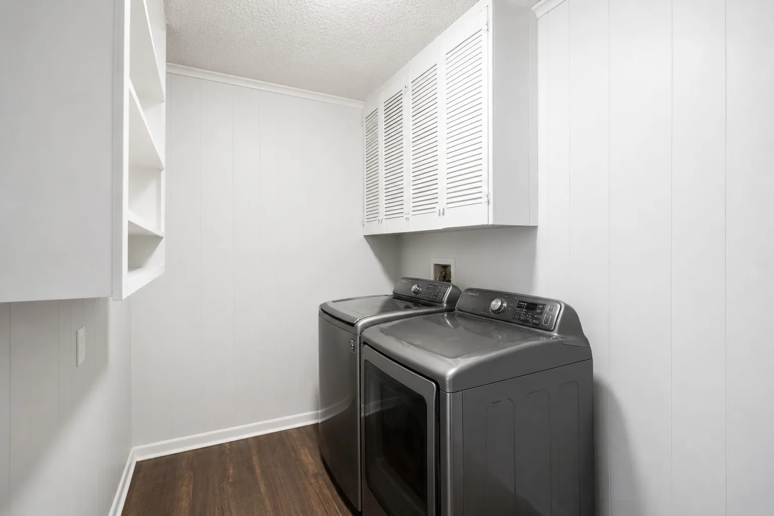Dedicated laundry space featuring wood-finish flooring and white vertical paneling