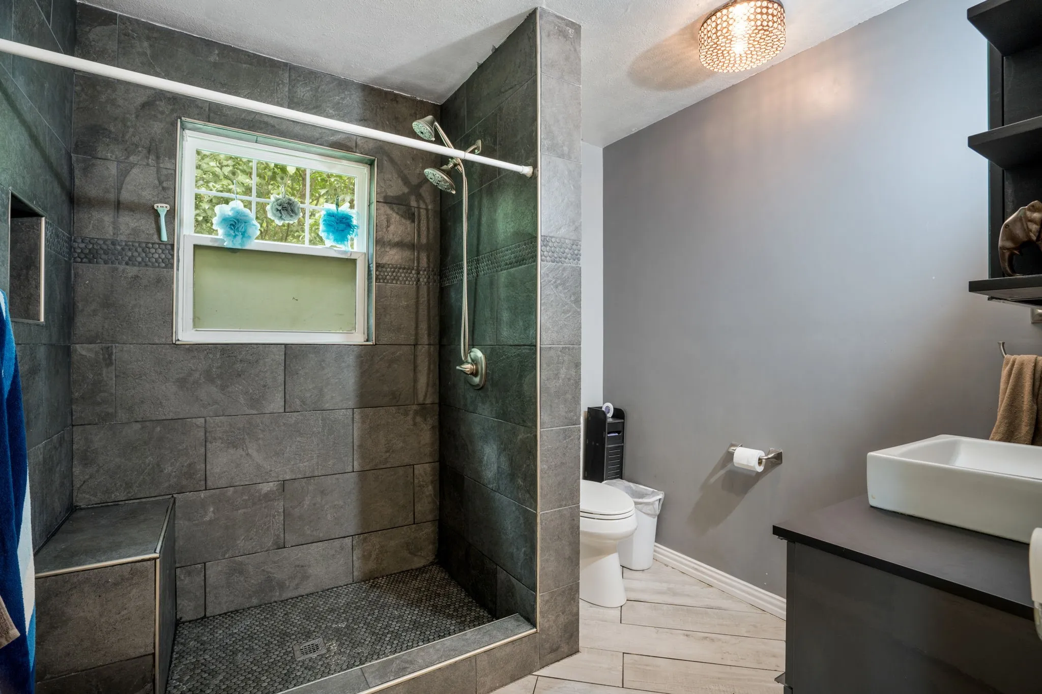 Walk-in shower featuring large format wall tile, a built-in bench, and a mosaic tile floor