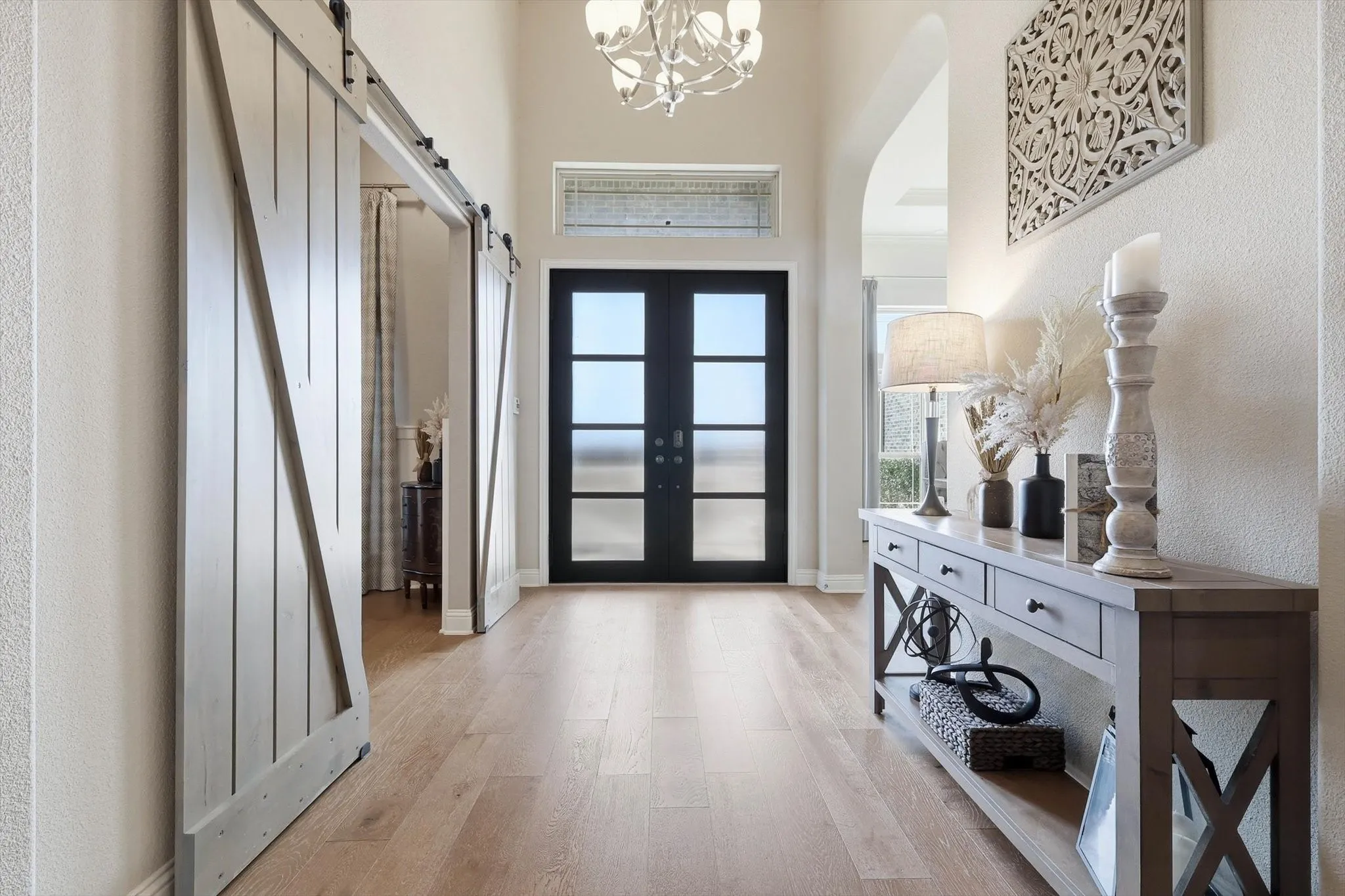 Foyer featuring light wood-finish flooring, a contemporary chandelier, and a transom window above the entry
