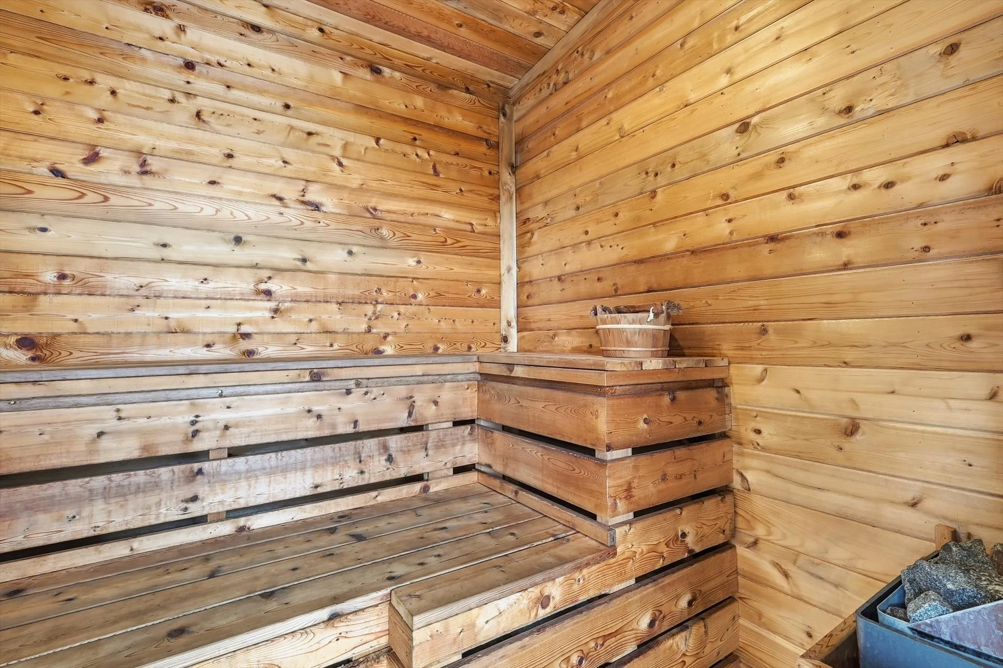 Custom sauna featuring natural wood paneling, multi-level slatted benches, and a dedicated sauna heater