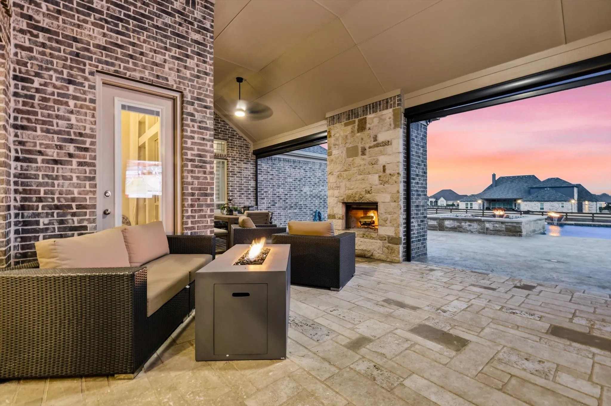 Covered patio with a stone fireplace and brick accents