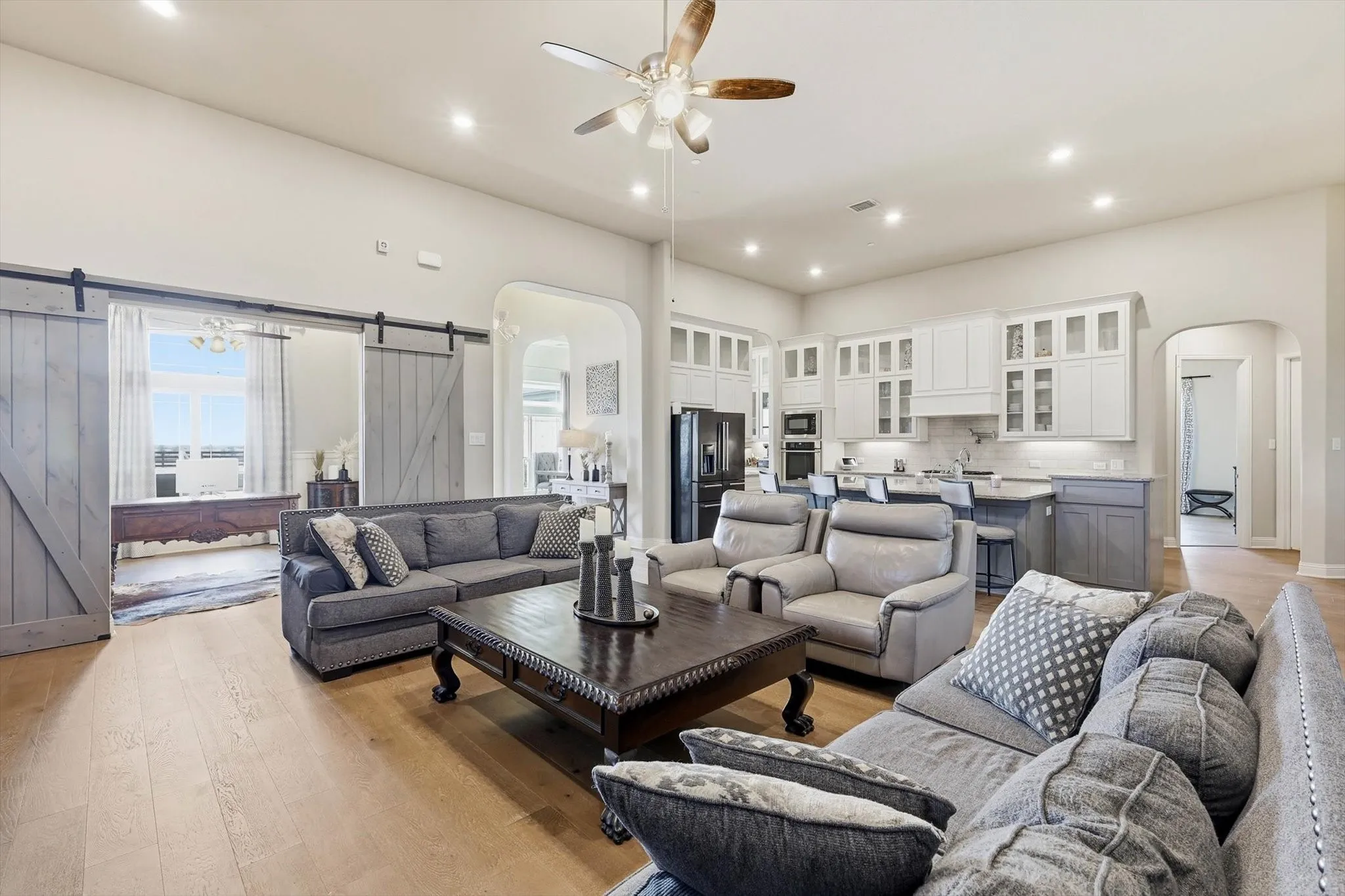Open-concept living area featuring light wood-finish flooring, recessed lighting, and a ceiling fan