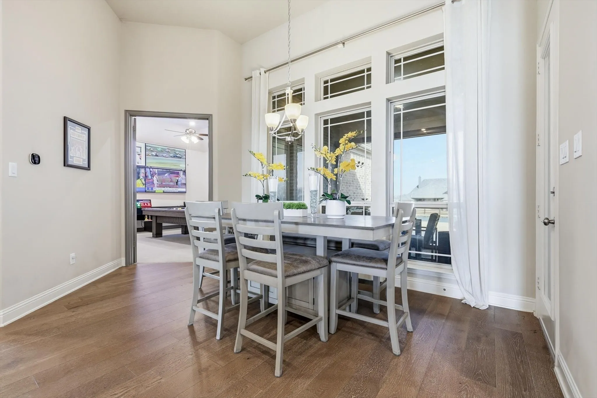 Dining area featuring wood-finish flooring, vaulted ceilings, and large windows with transom accents