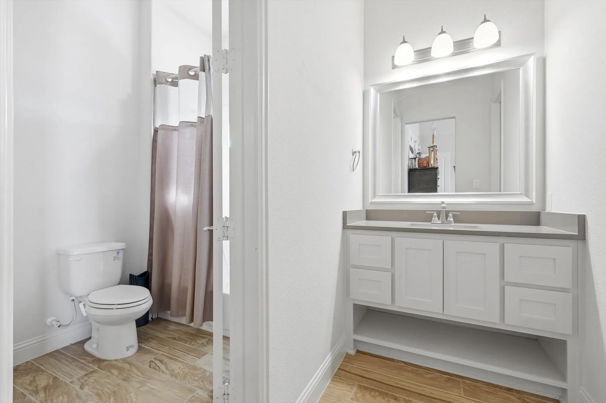 Bathroom featuring a white vanity with a gray countertop, an undermount sink, and a framed mirror