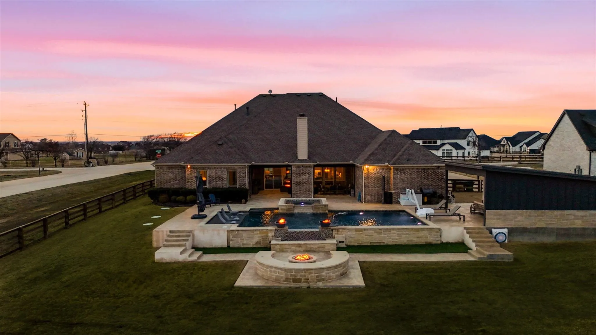 Brick exterior residence featuring a multi-level patio with a swimming pool, spa, and fire pit