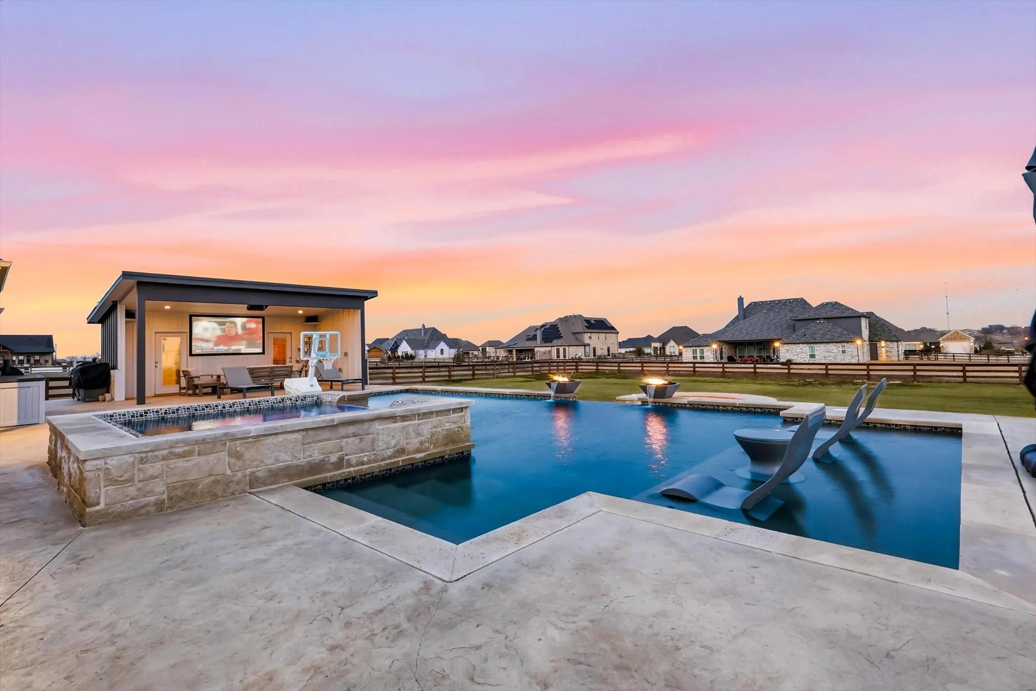 Expansive backyard featuring a rectangular pool with integrated lounge areas and water features
