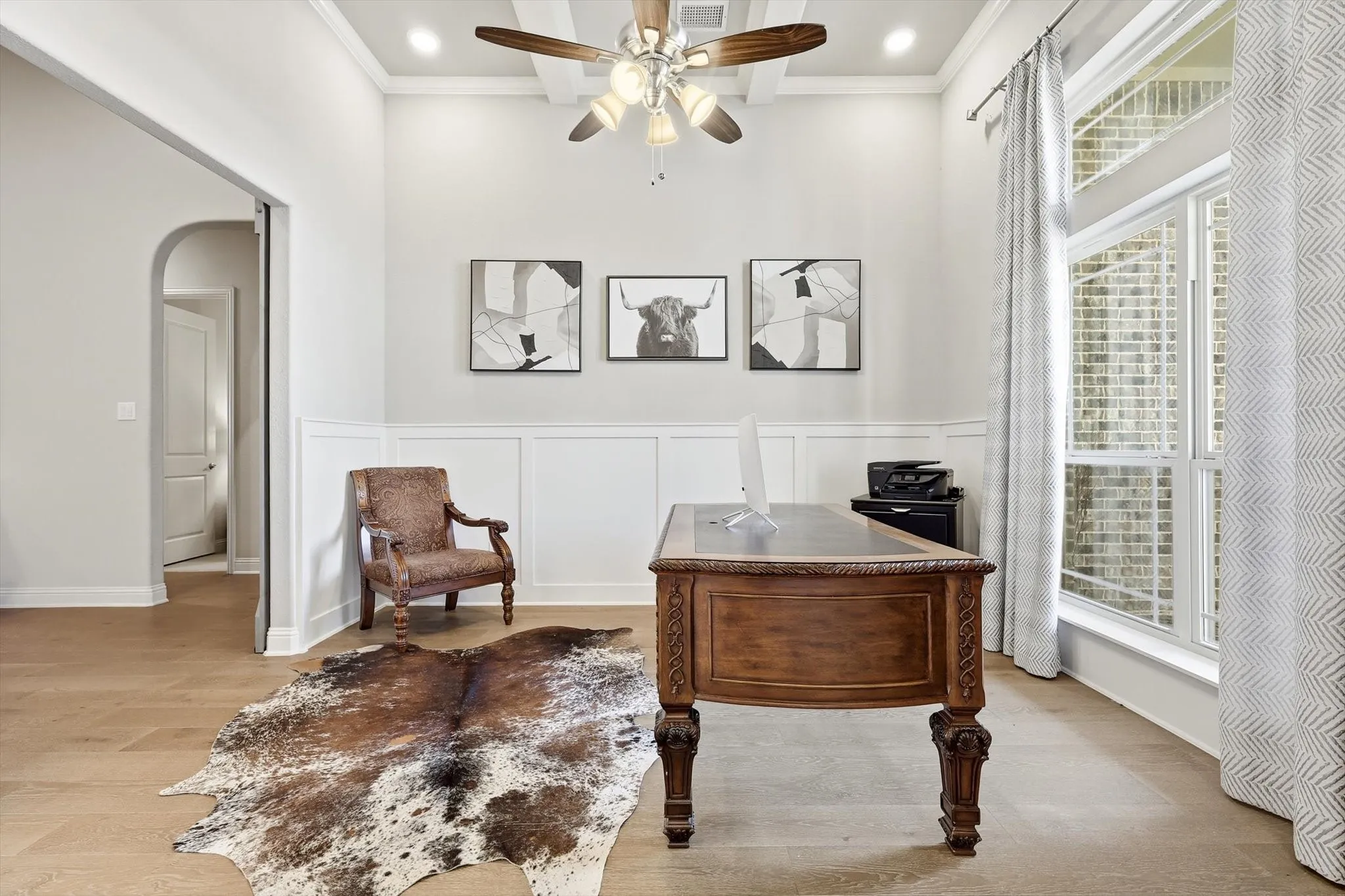 Room featuring wood-finish flooring, wainscoting, and a coffered ceiling with a ceiling fan