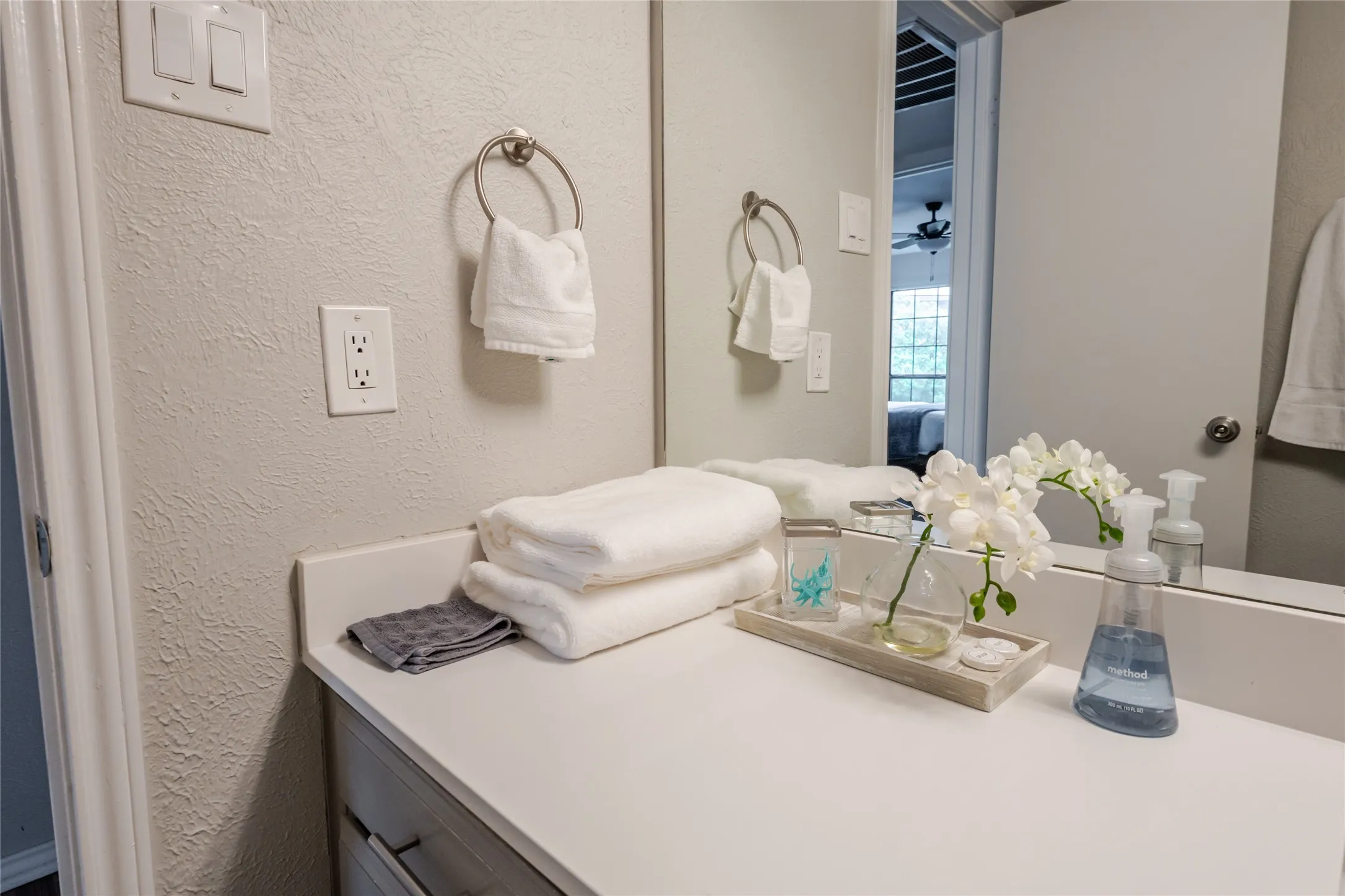 Bathroom vanity featuring a light-colored countertop, integrated sink, and an expansive wall mirror