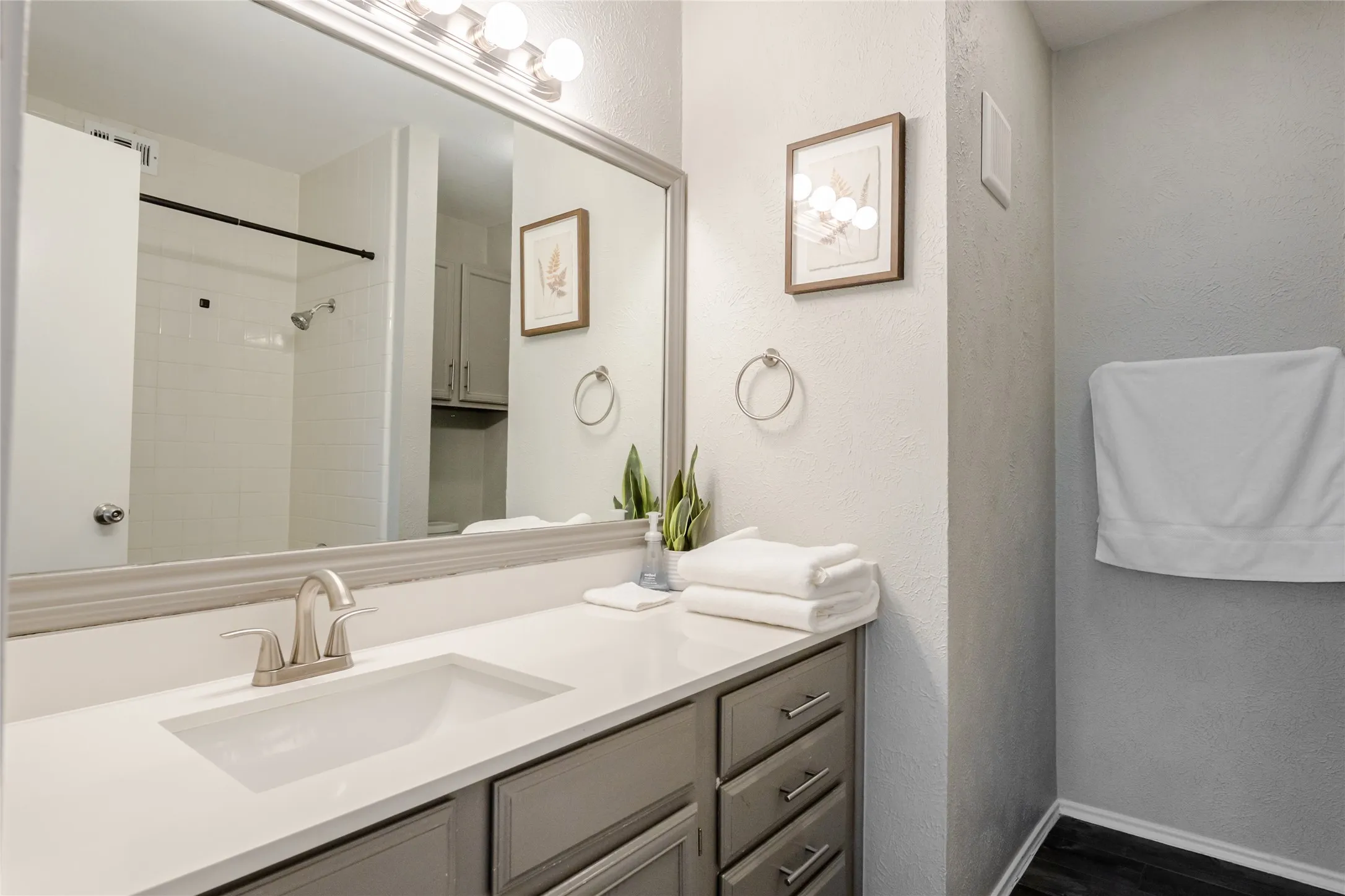 Bathroom vanity featuring a light gray base cabinet with brushed nickel hardware, a white countertop, and an undermount sink with a brushed nickel faucet
