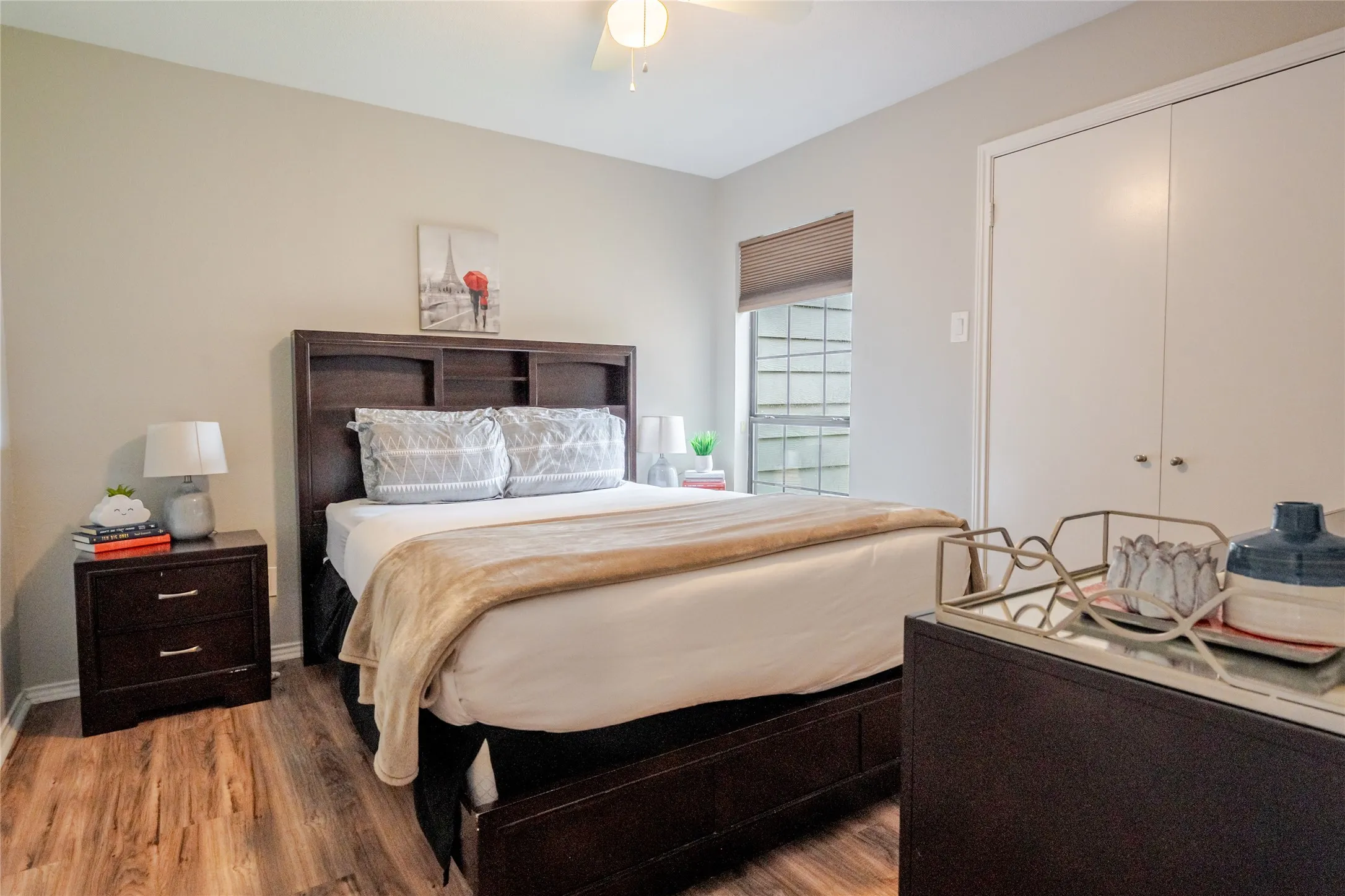 Spacious room featuring wood-finish flooring, a ceiling fan, and a large window with privacy blinds