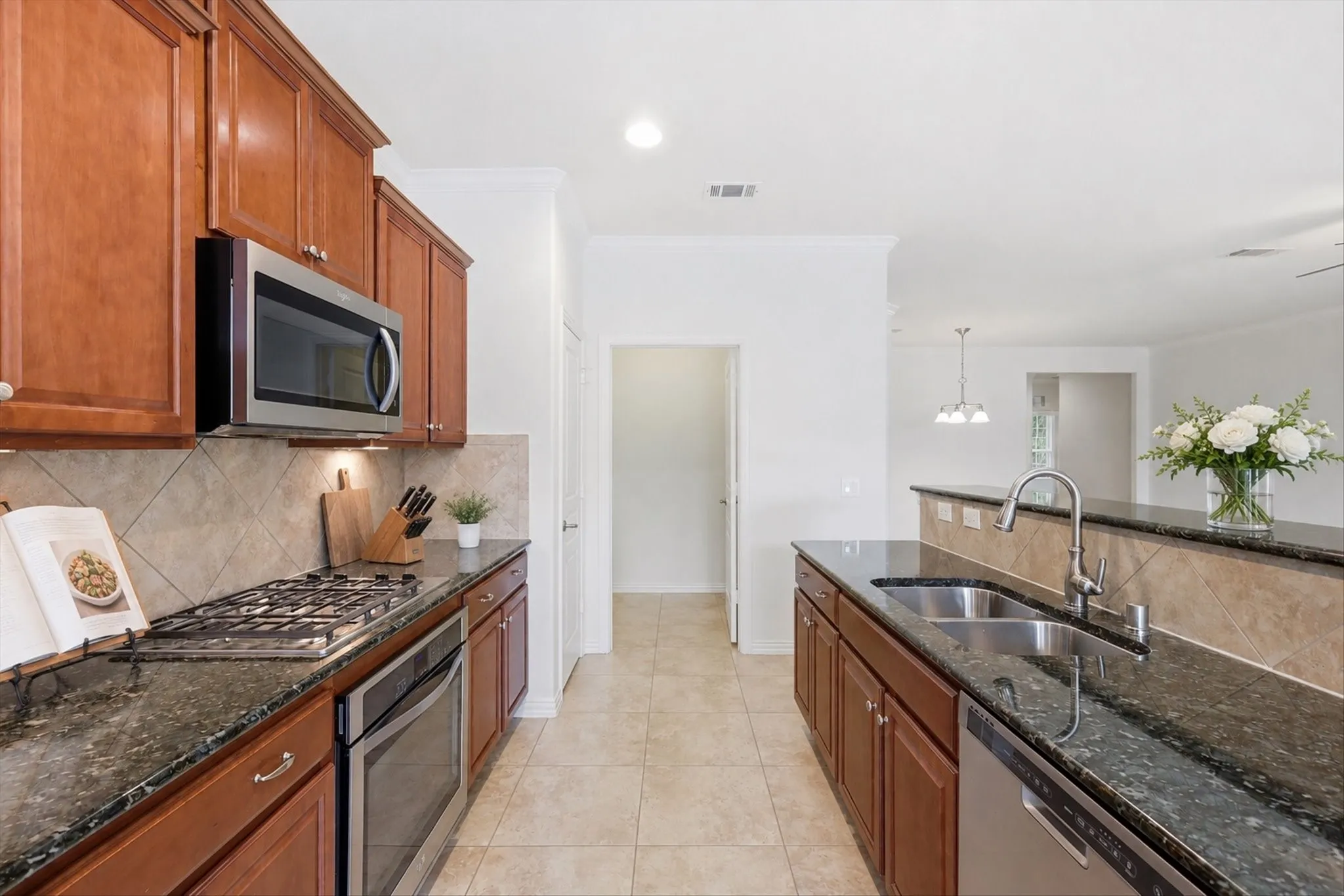 Modern kitchen featuring rich wood cabinetry, stainless steel appliances, granite countertops, and a tile backsplash