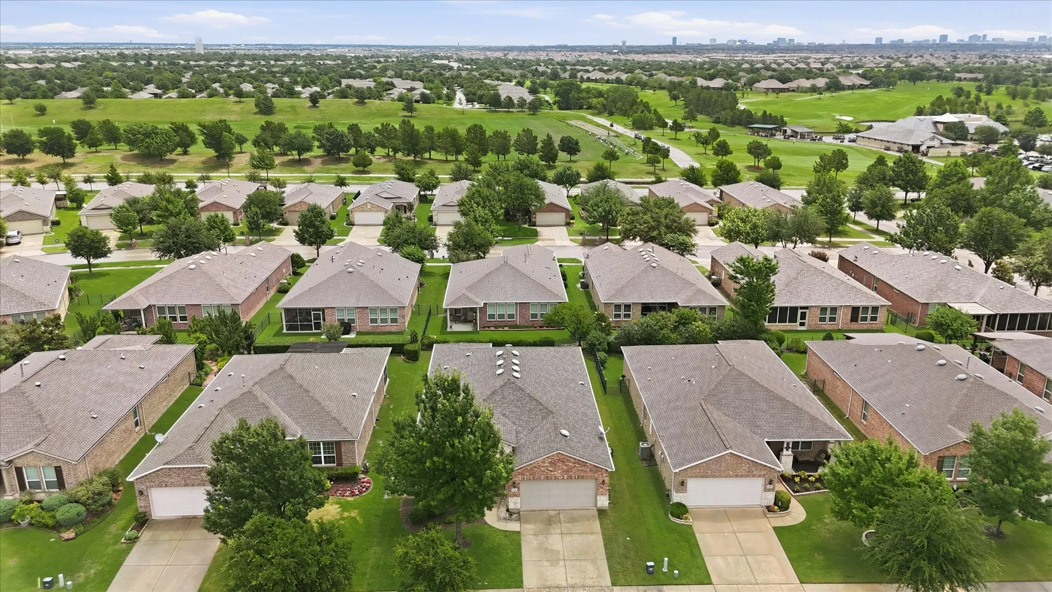 Suburban residential development featuring single-story homes with brick exteriors, attached garages, and pitched shingle roofs