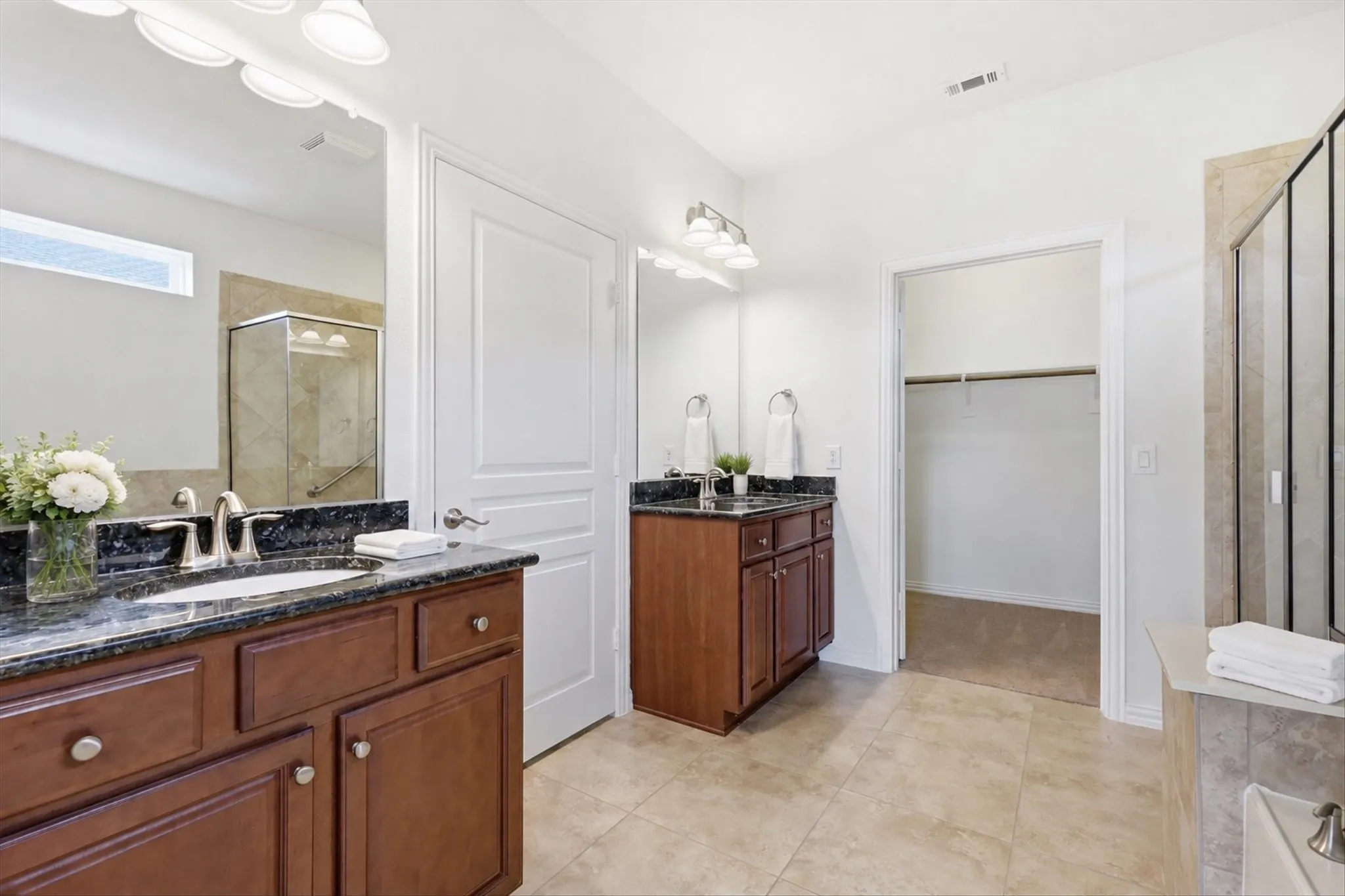 Dual wood-finish vanities with dark countertops and undermount sinks