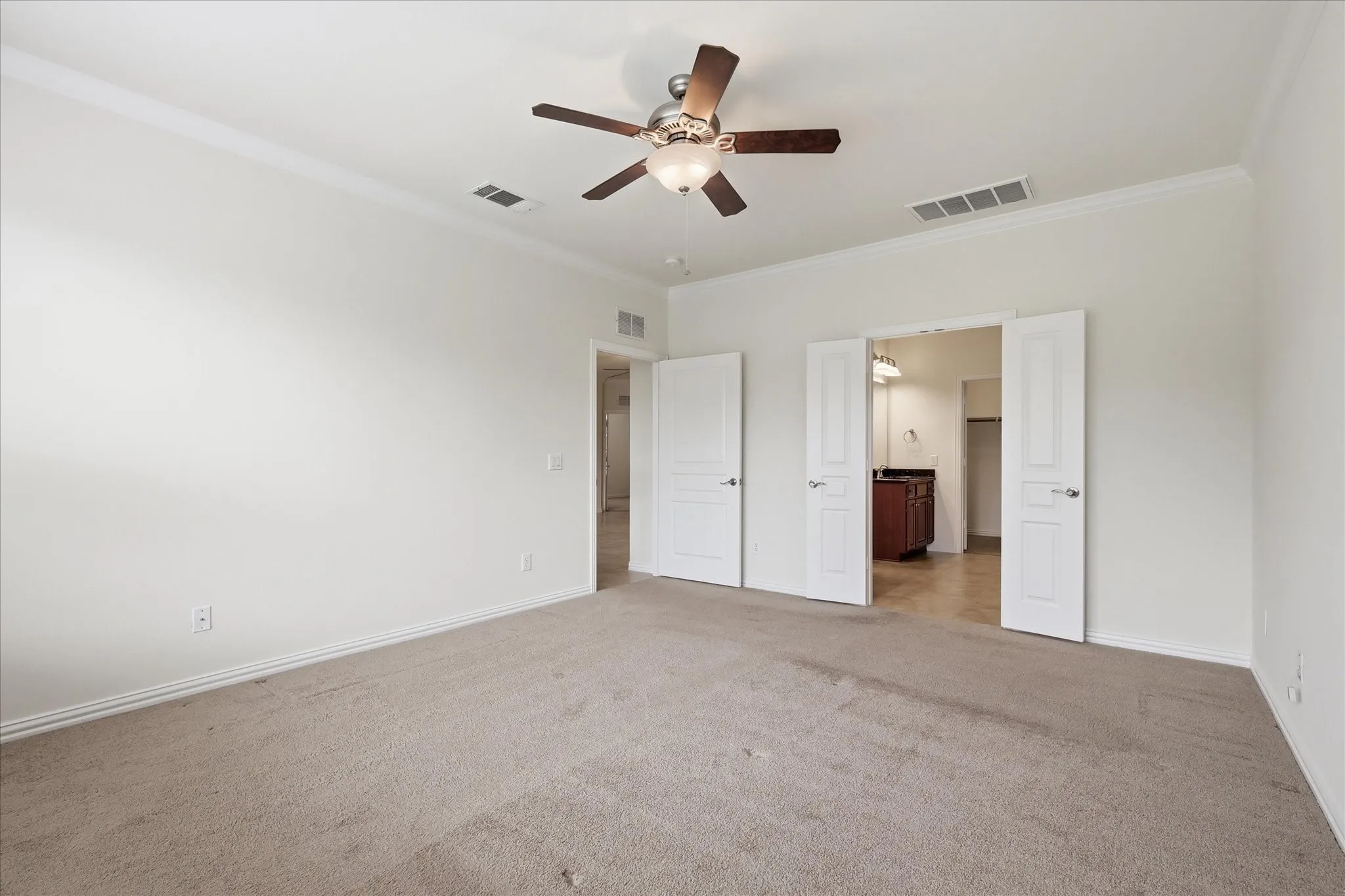 Neutral tone carpeted room with crown molding and ceiling fan