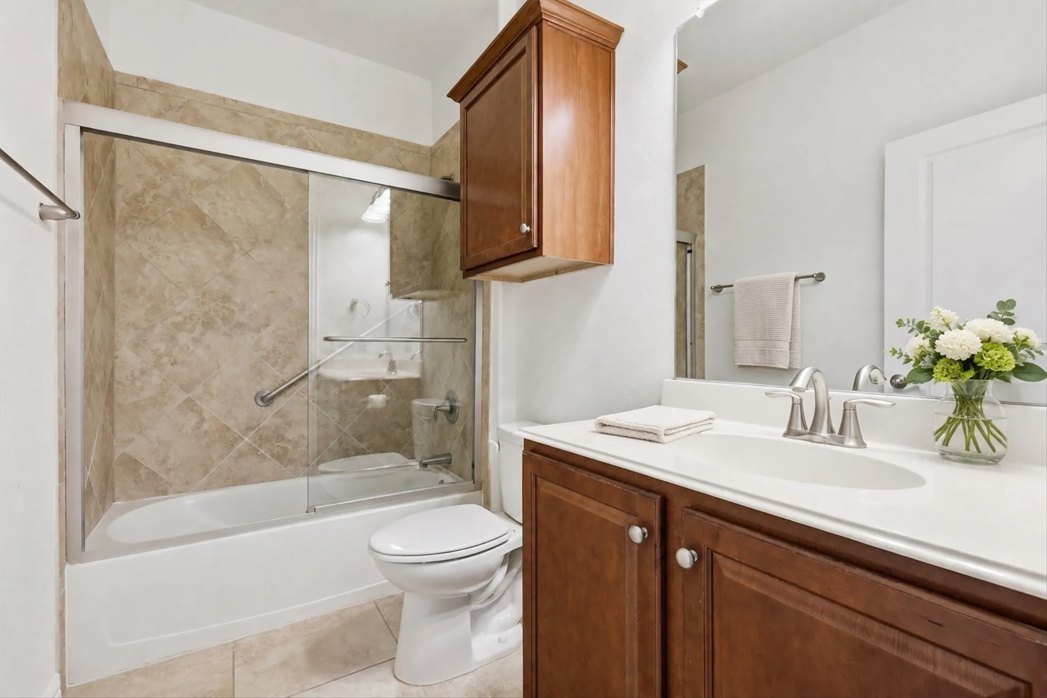 Bathroom featuring a tub/shower combination with sliding glass doors, neutral tiled surround, and a grab bar