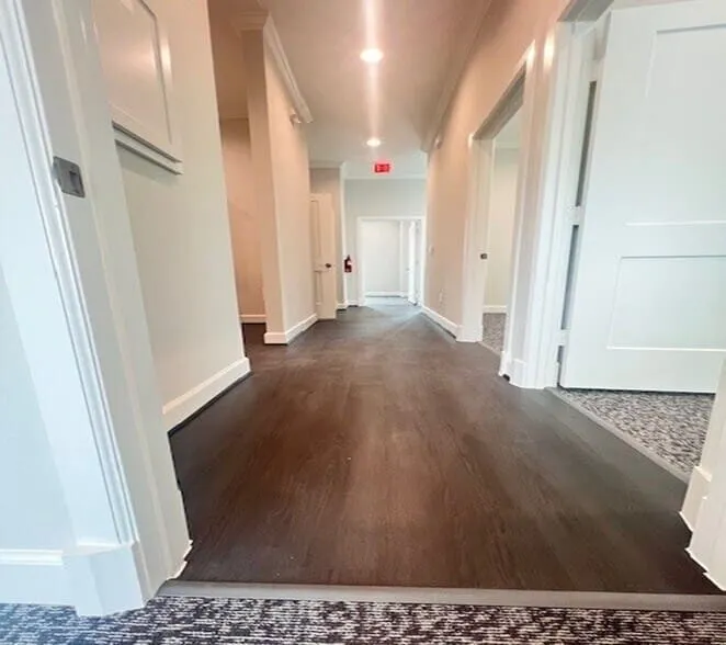 Hallway featuring dark wood-finish flooring, recessed lighting, white baseboards, and white paneled doors