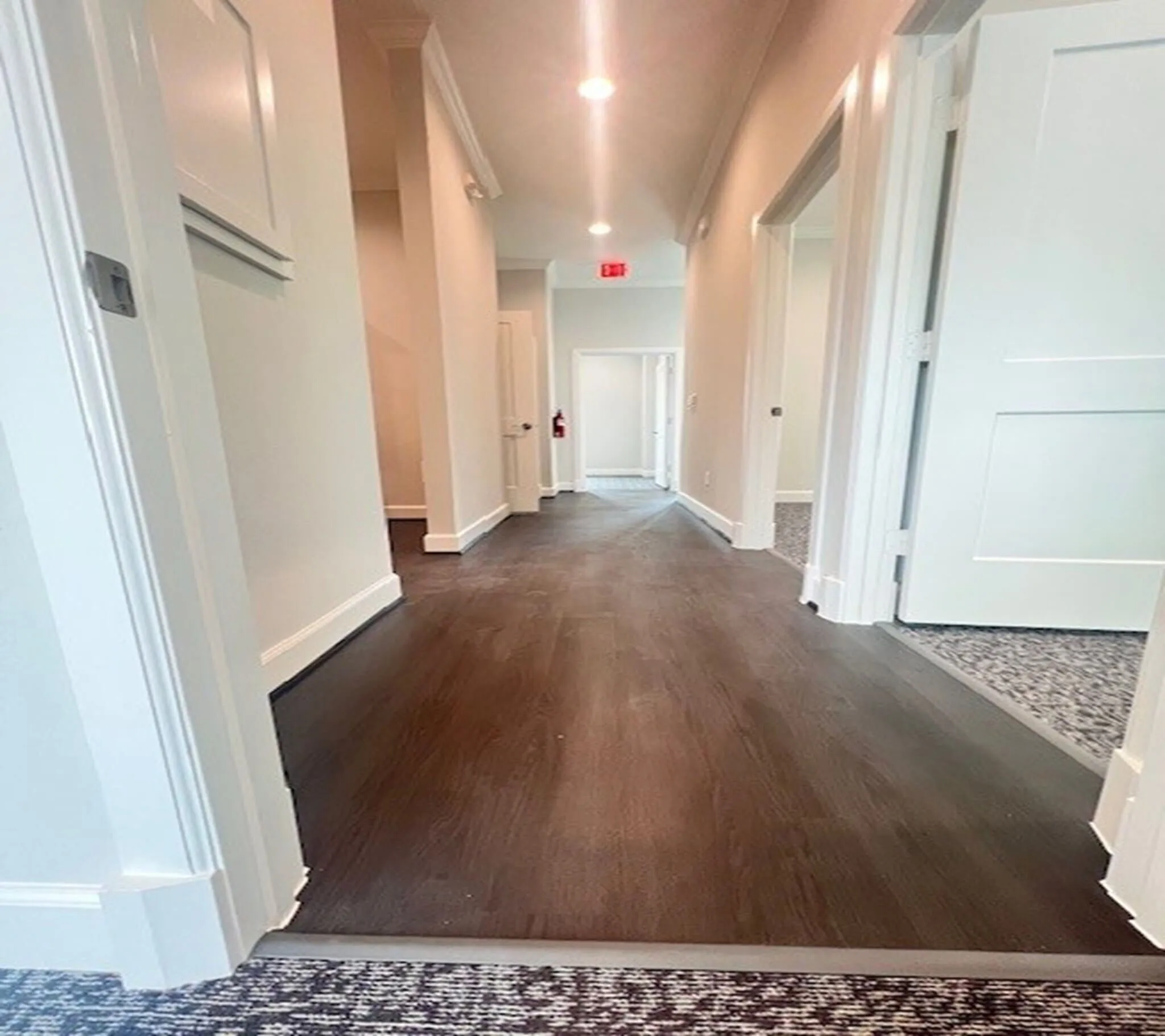 Hallway featuring dark wood-finish flooring, white baseboards, and overhead recessed lighting