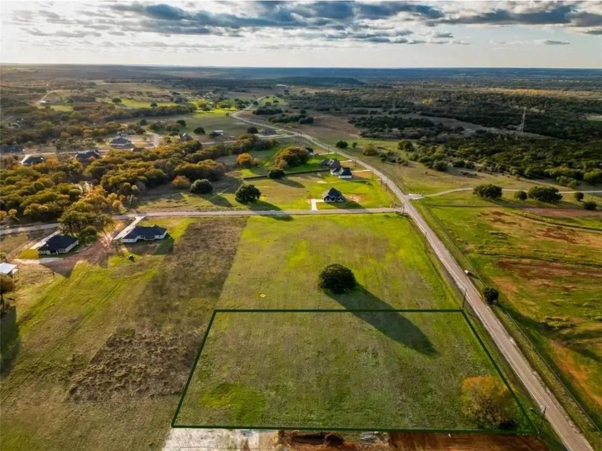 Expansive land parcel featuring open green space and scattered trees