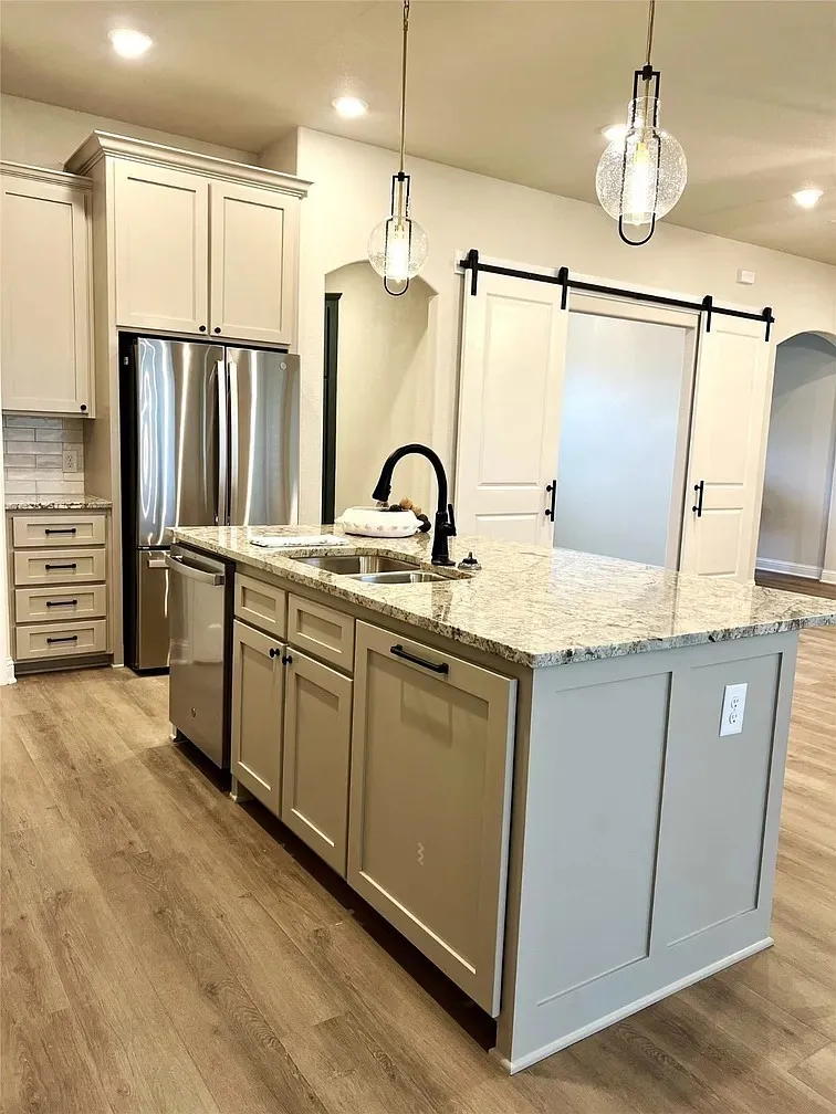 Kitchen island featuring a double-basin sink with a matte black faucet, granite countertops, and wood-finish flooring